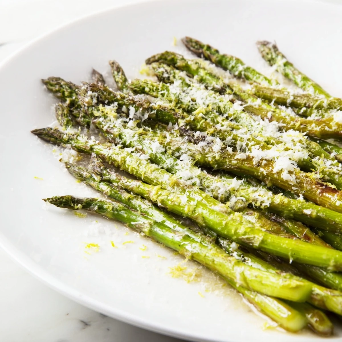 Tender roasted asparagus spears topped with golden Parmesan cheese and lemon zest, served warm as an easy vegetarian side.