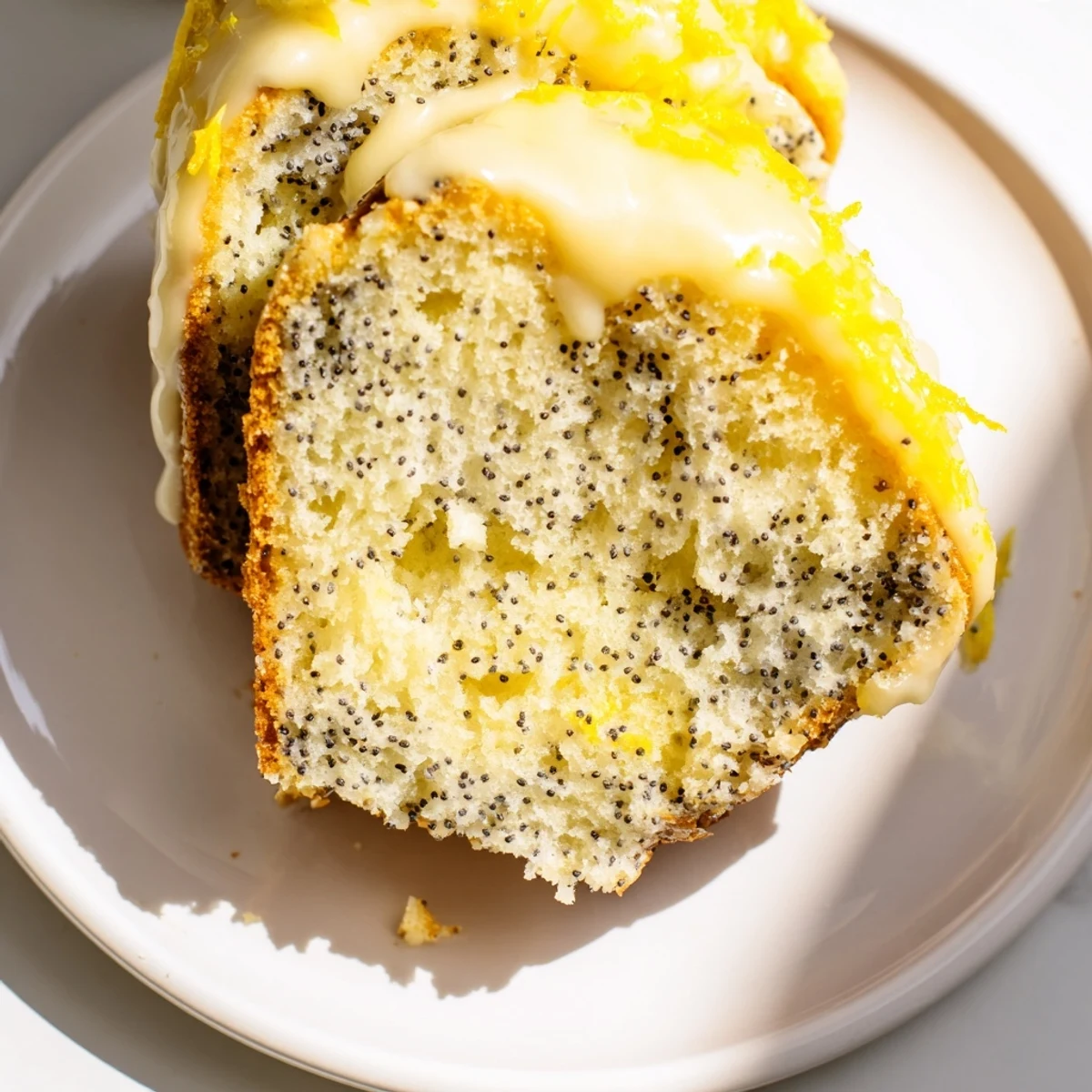 Freshly baked Lemon Poppy Seed Bundt Cake with a generous drizzle of lemon cream glaze dripping down the ridges.