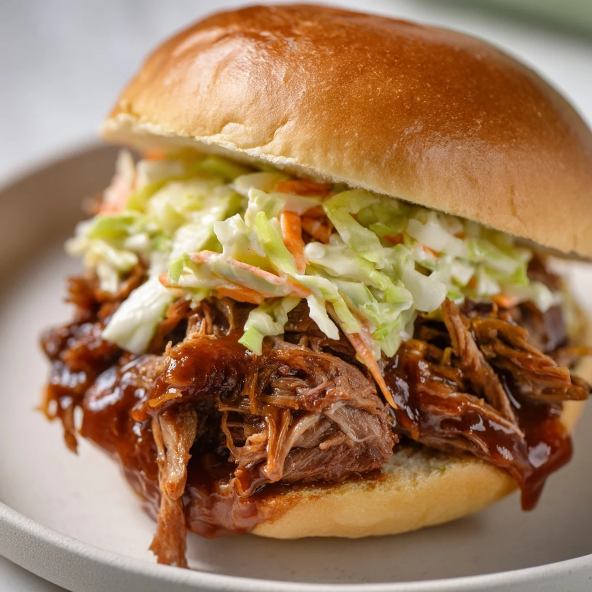Slow Cooker Pulled Beef Sandwiches with Coleslaw served on a toasted bun with a side of chips.