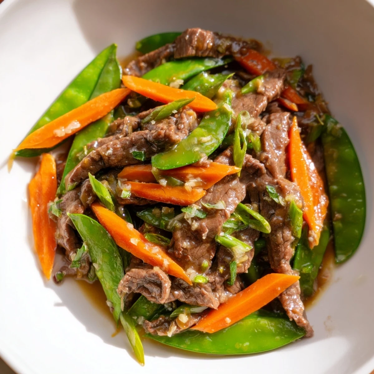 Sizzling slices of beef mix with crisp snow peas and orange carrots in a savory stir-fry.