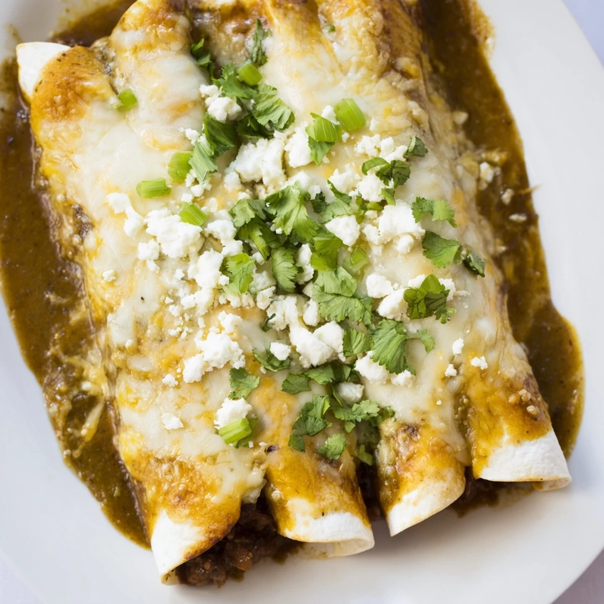 Bubbling Beef Enchiladas with Green Sauce baked in a dish, topped with melted cheese and cilantro for a Tex-Mex family dinner.