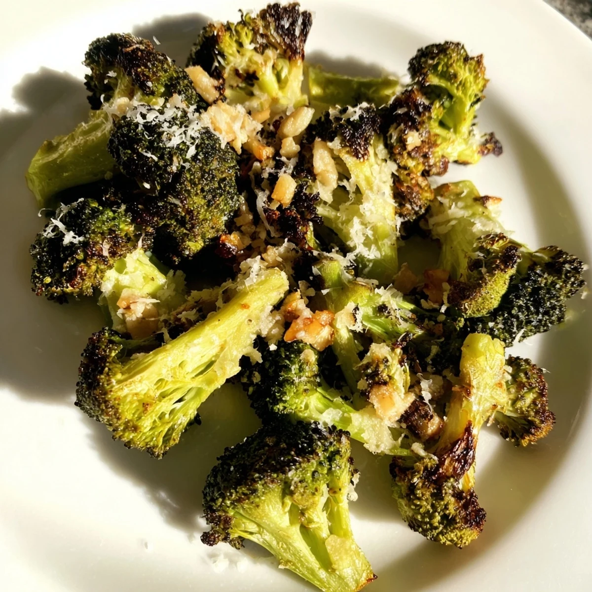 Freshly roasted broccoli florets with minced garlic and grated Parmesan, ready to serve hot from the oven.