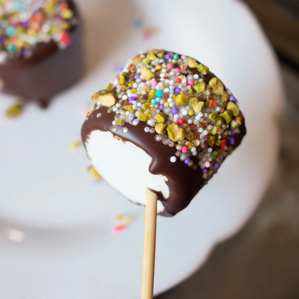 Upright chocolate marshmallows on a stick, dipped in melted chocolate and finished with desiccated coconut and chopped nuts.