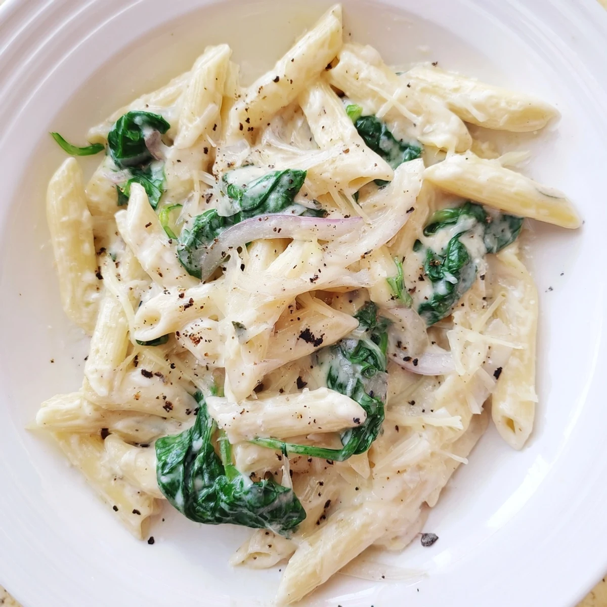 Creamy Spinach Pasta with Garlic in a skillet, featuring wilted greens in a velvety Parmesan sauce, ready to serve.