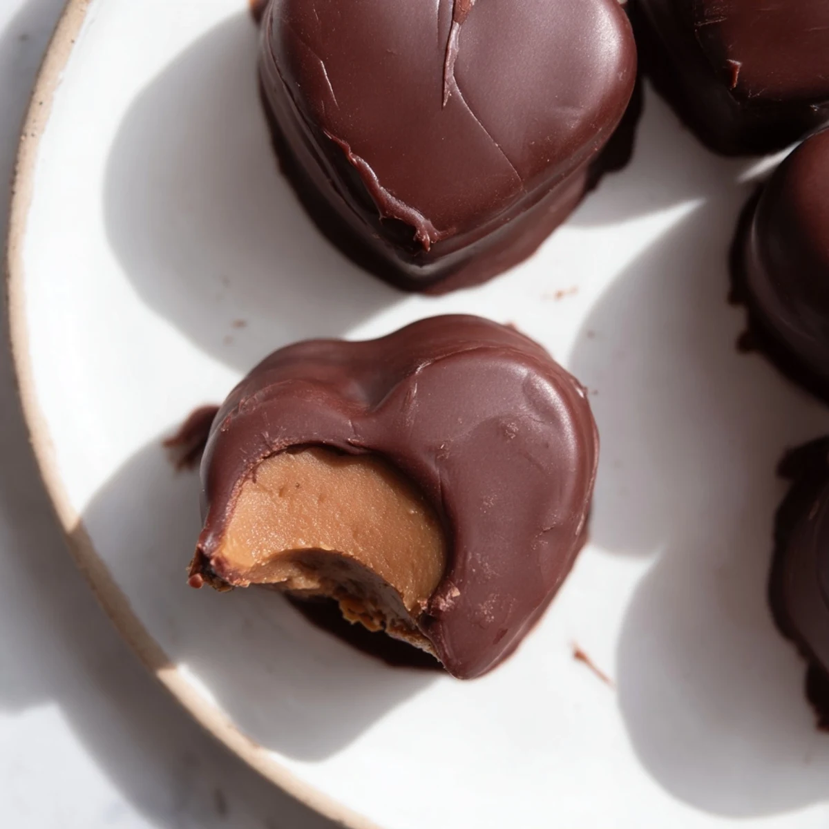 Close-up of a half-dipped chocolate peanut butter heart revealing a creamy peanut butter filling and rich cocoa.