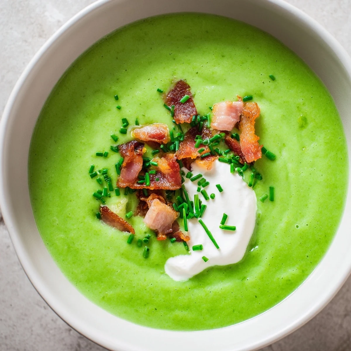 Bowl of Spring Pea Soup with Crispy Turkey Bacon beside fresh mint and crusty bread.