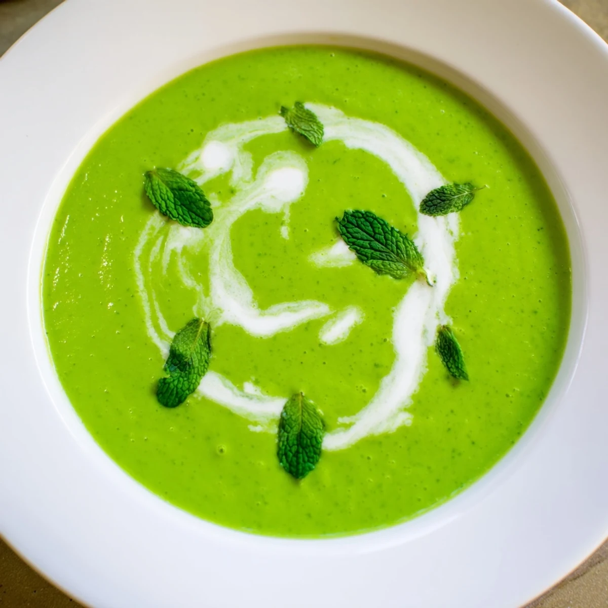 Spoon dipping into Spring Pea Soup with Mint and Crème Fraîche, steam rising from the warm, silky broth.
