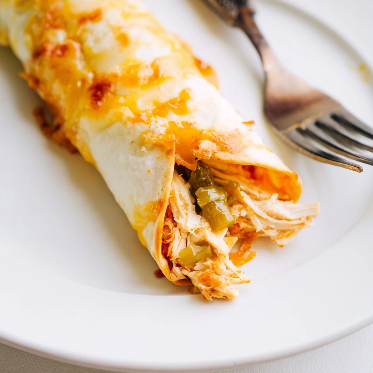 Close-up of a Dill Pickle Ranch Chicken Taquito broken in half, highlighting the tangy dill pickle and ranch chicken mixture with melted cheddar cheese ooze.