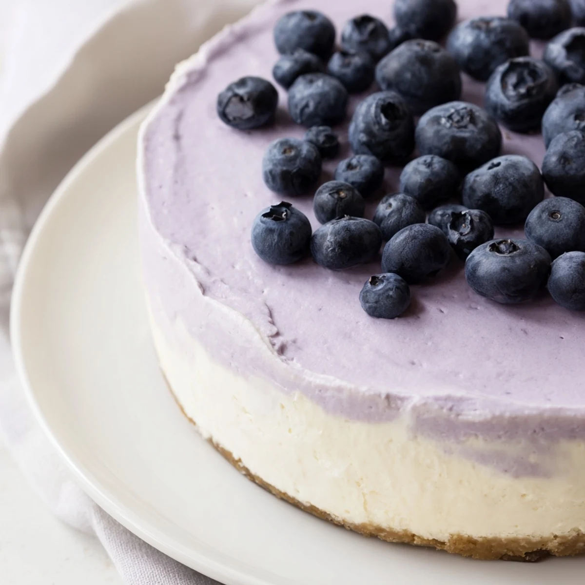 A slice of Blueberry Mousse Cheesecake with a creamy filling and fresh berry topping on a rustic table.