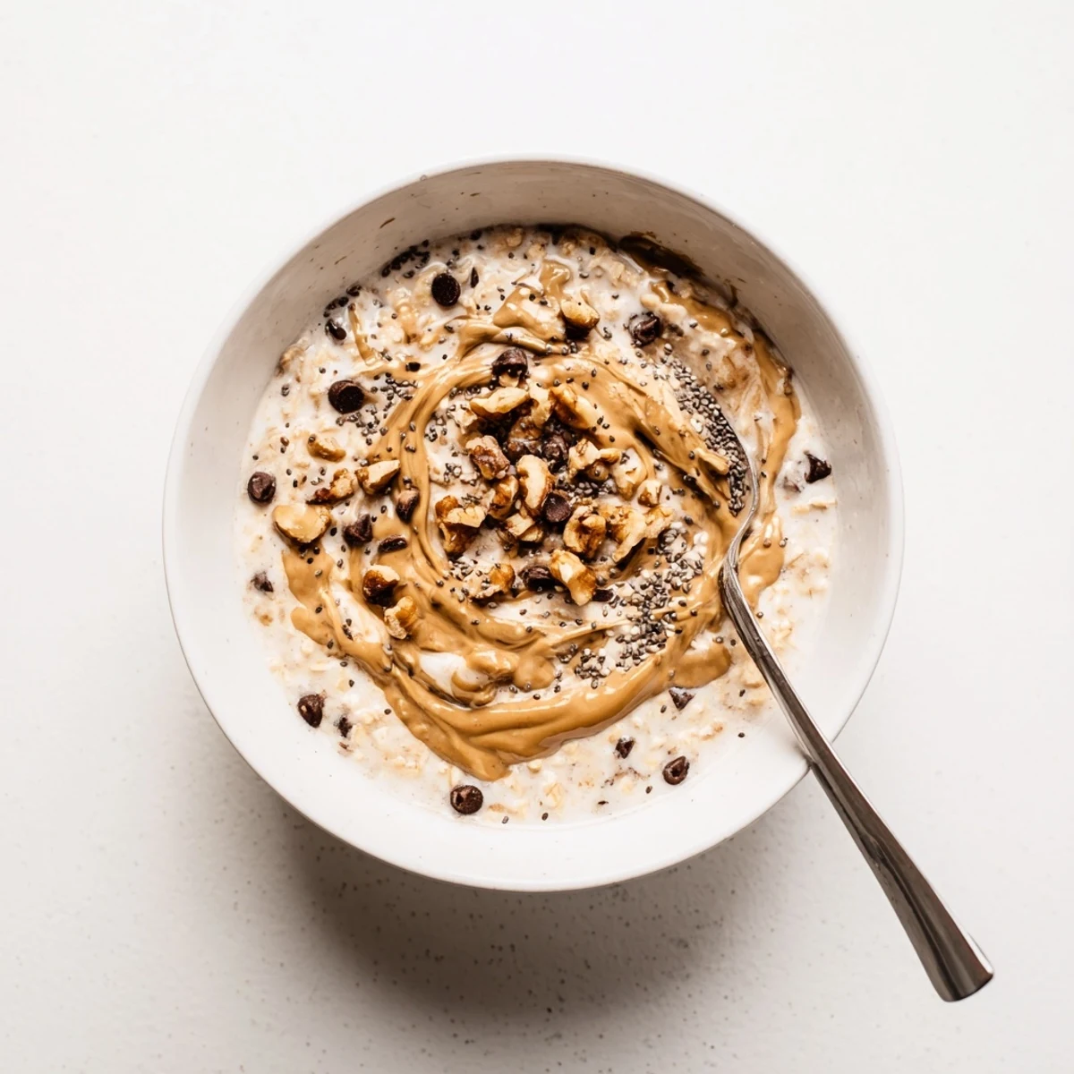 Layered Cookie Dough Overnight Oats with Greek yogurt, maple syrup, and walnuts, ready to enjoy cold on a busy morning.