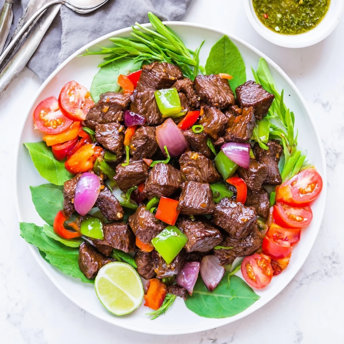 Steam rises from jasmine rice beside colorful Vietnamese Shaking Beef served with a tangy lime dipping sauce.