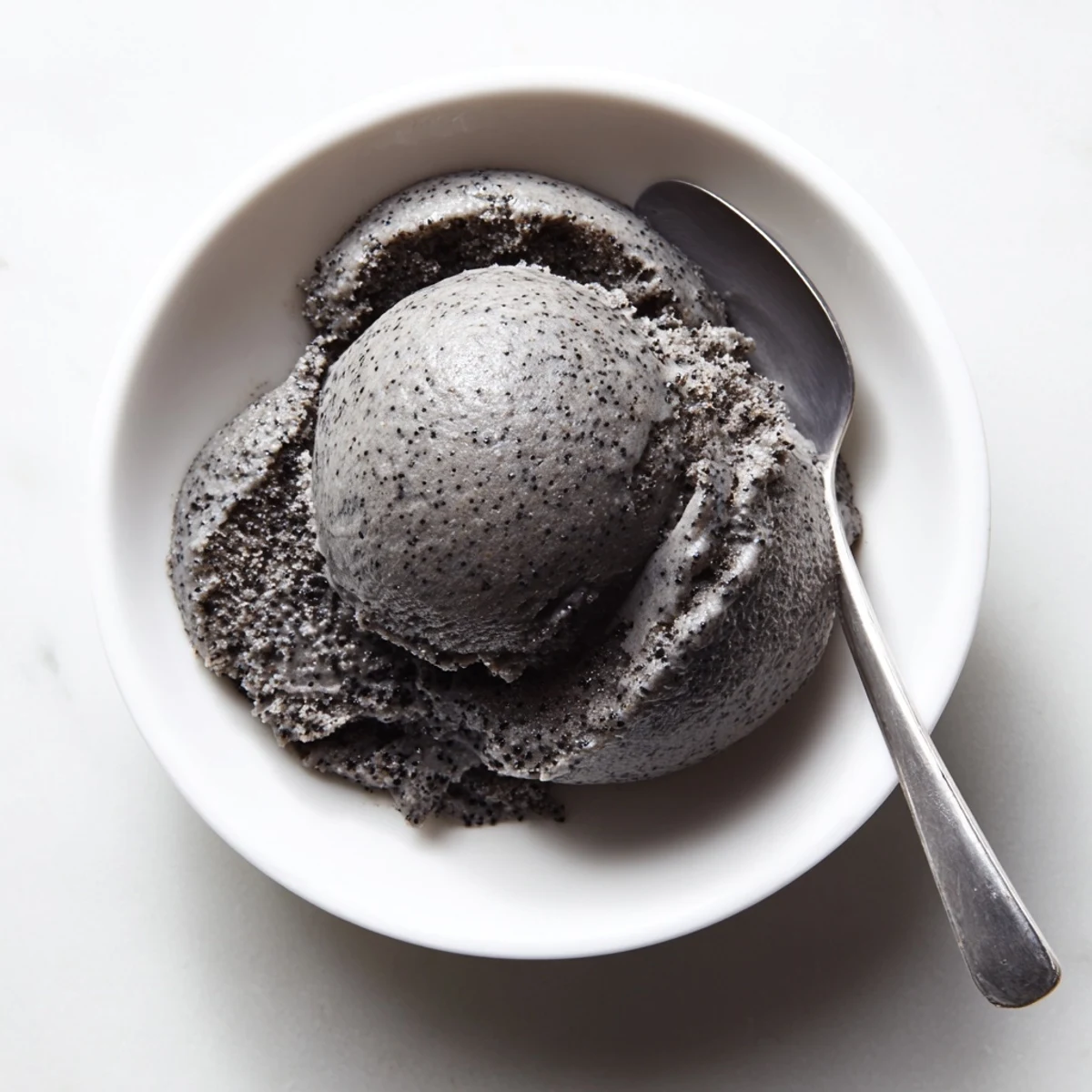 Rich homemade Toasted Black Sesame Ice Cream in a waffle cone, showcasing its deep gray swirls and nutty aroma.