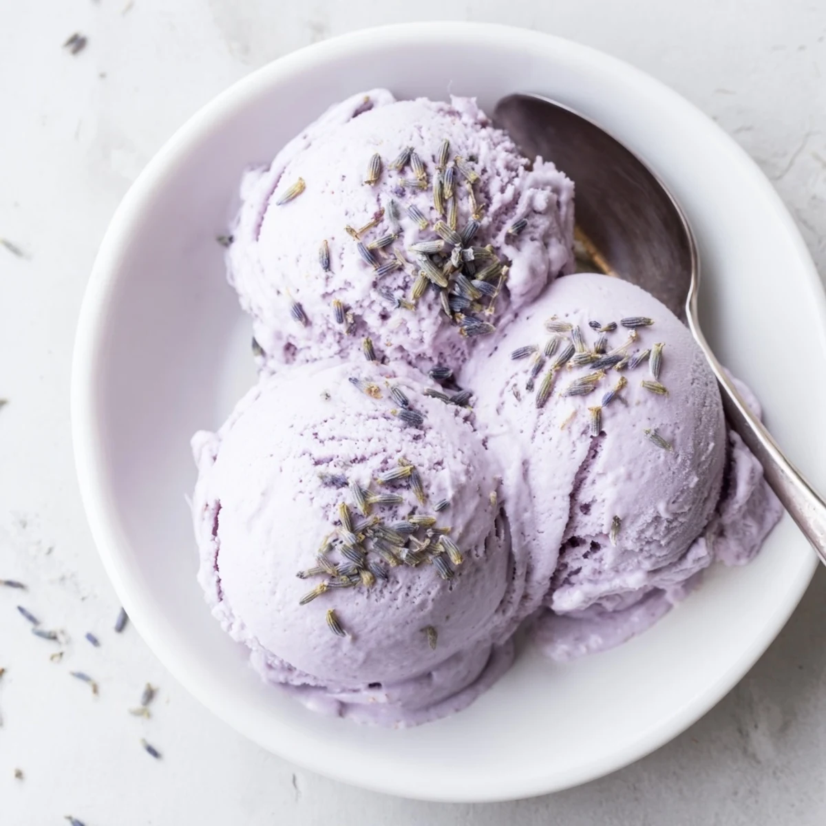 A close-up view shows the smooth, pale purple Lavender Ice Cream with a delicate sprinkle of lavender buds on top.