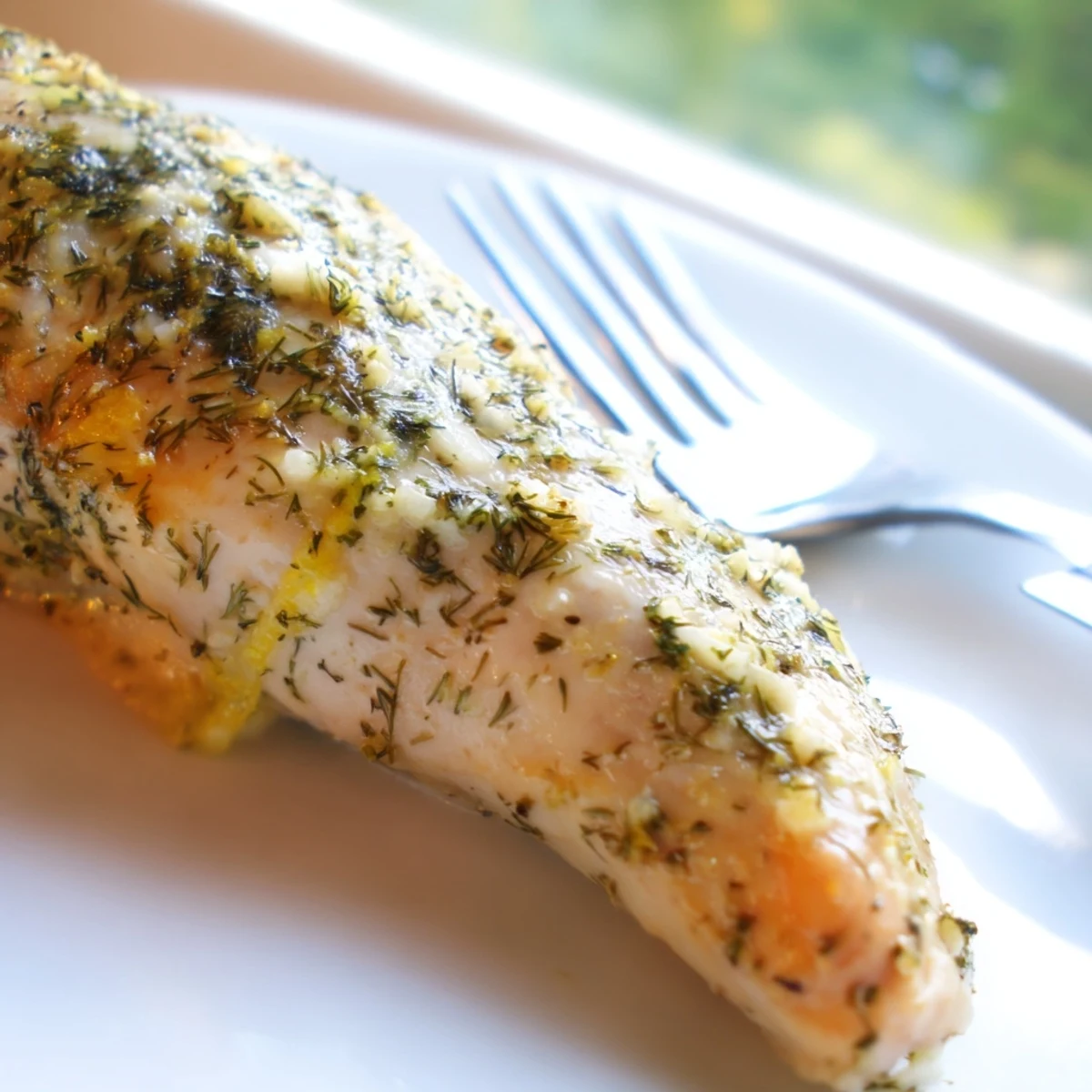 Tender Paleo Lemon Dill Chicken breasts featuring a vibrant marinade with lemon zest and dill on a rustic wooden table.