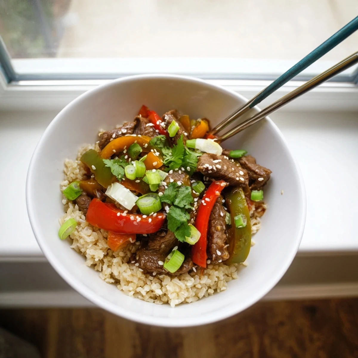 Healthy beef and pepper rice bowl featuring tender beef strips with colorful bell peppers in a savory garlic-ginger sauce over fluffy brown rice