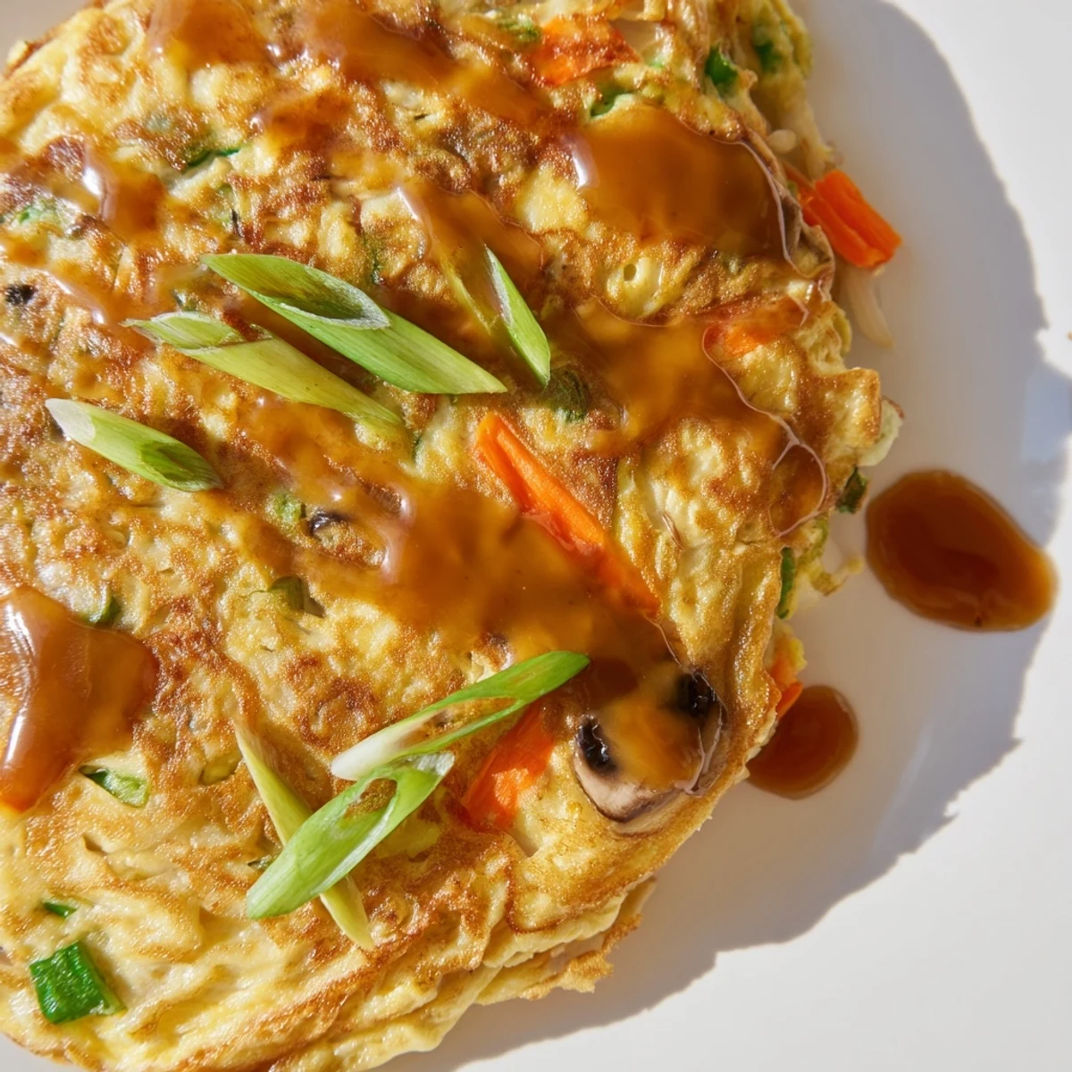Vegetable-packed Egg Foo Young served hot with thick savory gravy over steamed white rice
