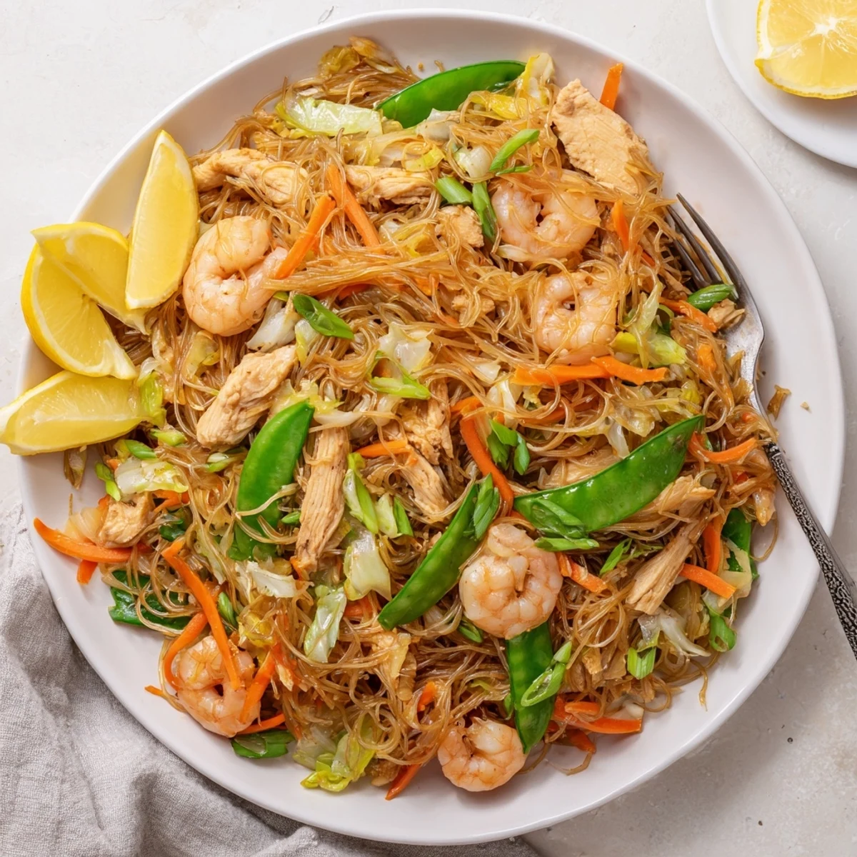 Sizzling plate of Traditional Pancit Bihon topped with tender chicken, shrimp, and crisp colorful vegetables