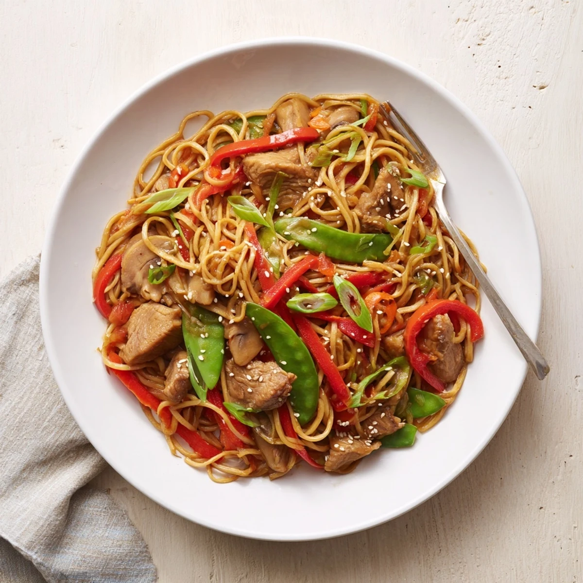Golden noodles tossed with tender chicken and crisp colorful vegetables in a rich soy-garlic sauce, garnished with sesame seeds and green onions.