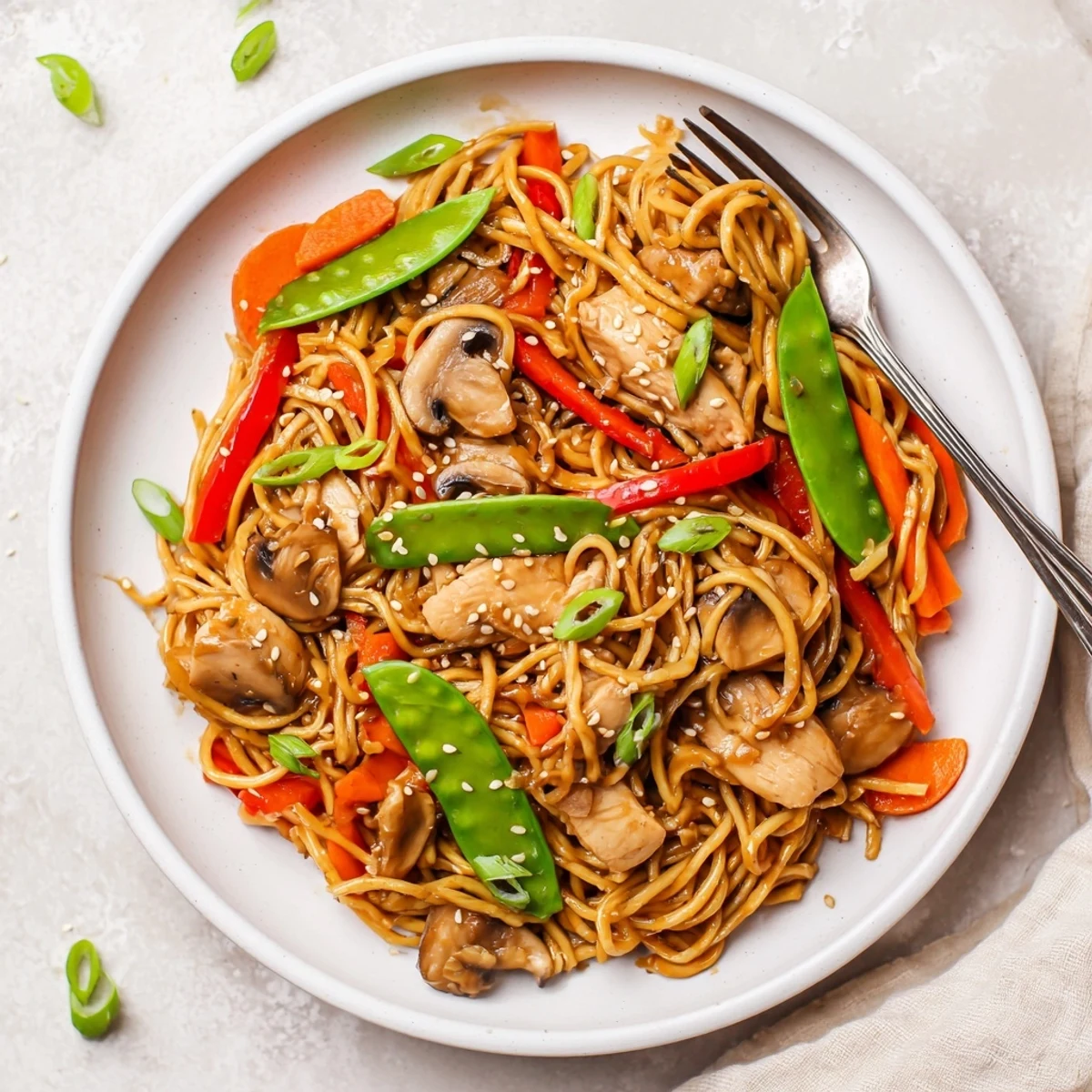 Slow cooker chicken lo mein featuring juicy meat, bell peppers, carrots, and mushrooms coated in a glossy brown Asian-style sauce.