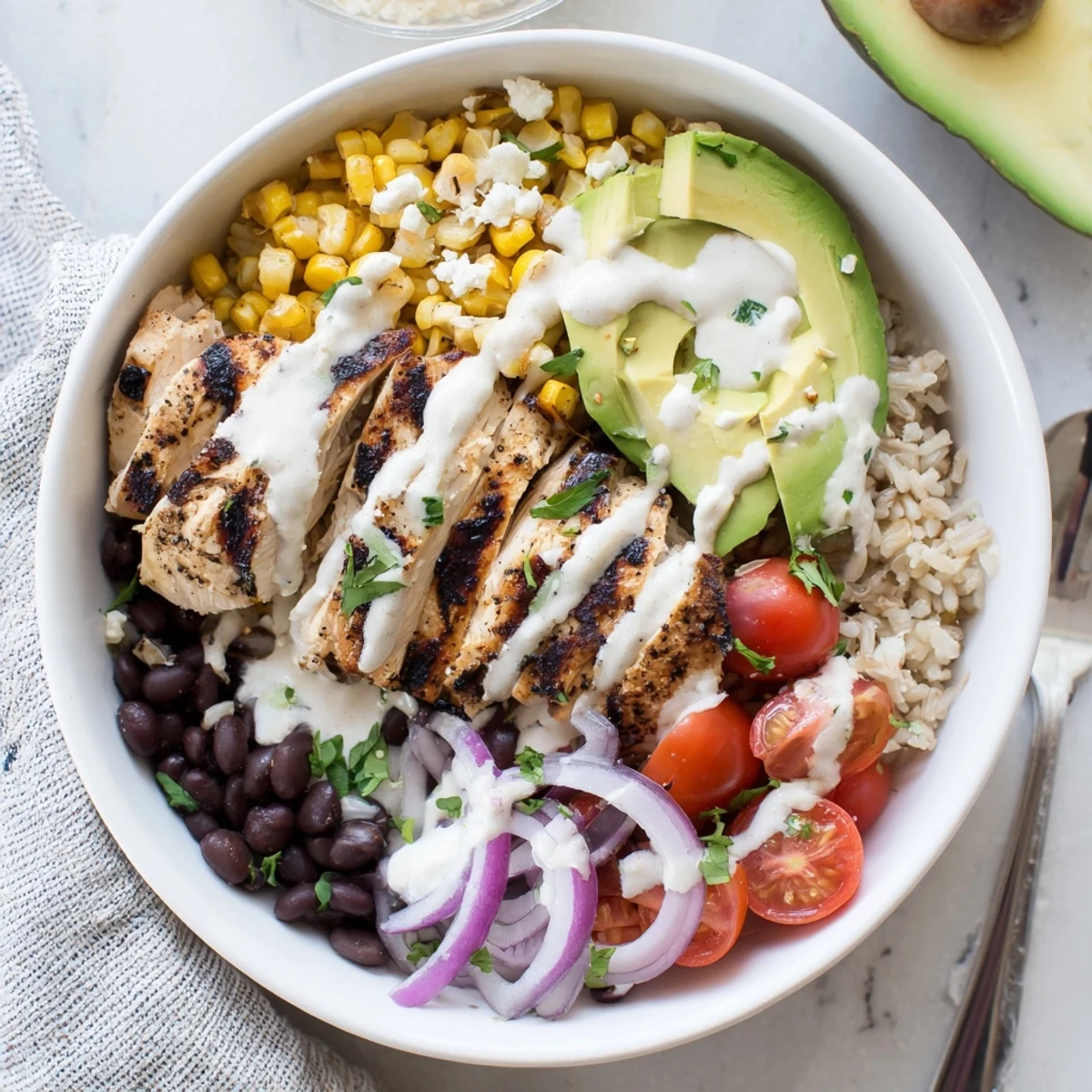 Golden grilled chicken slices atop colorful protein packed street corn chicken bowl with charred corn, black beans, and creamy yogurt lime dressing