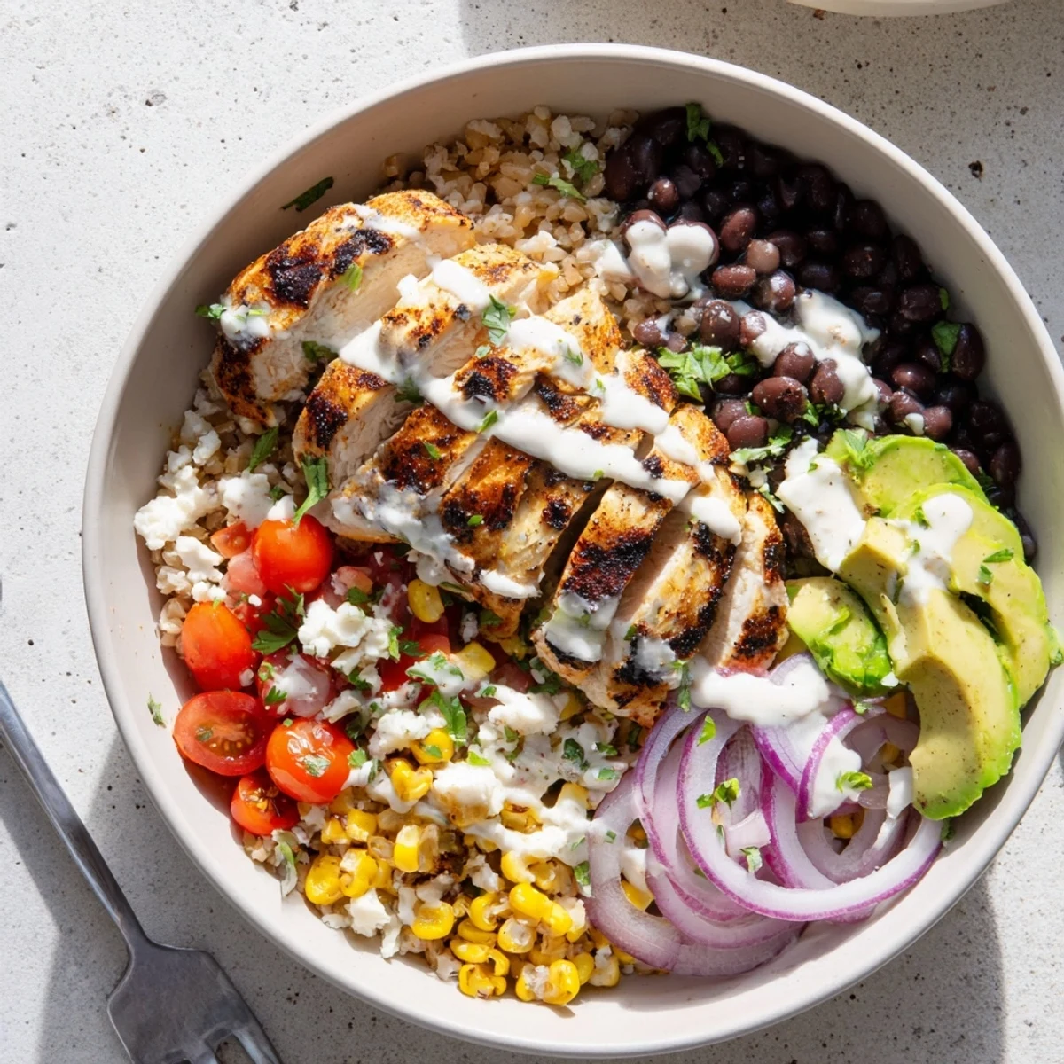 Vibrant protein packed street corn chicken bowl featuring juicy spiced chicken, sweet corn, avocado, and zesty lime drizzle over fluffy rice