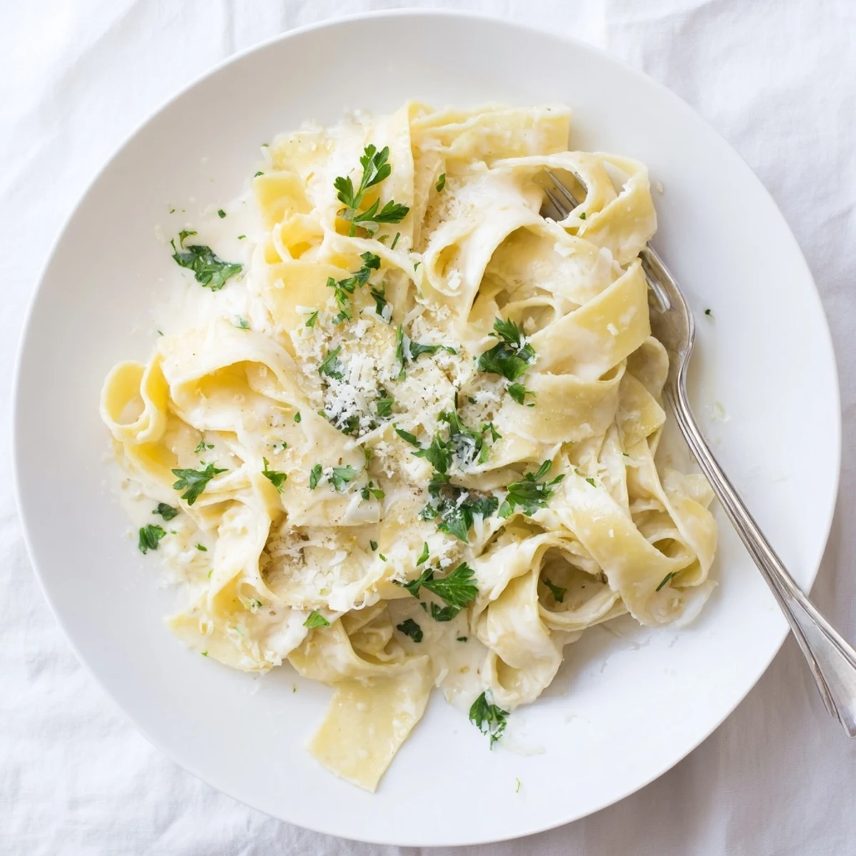 Steaming bowl of ultimate creamy fettuccine Alfredo sprinkled with Parmesan and vibrant green parsley
