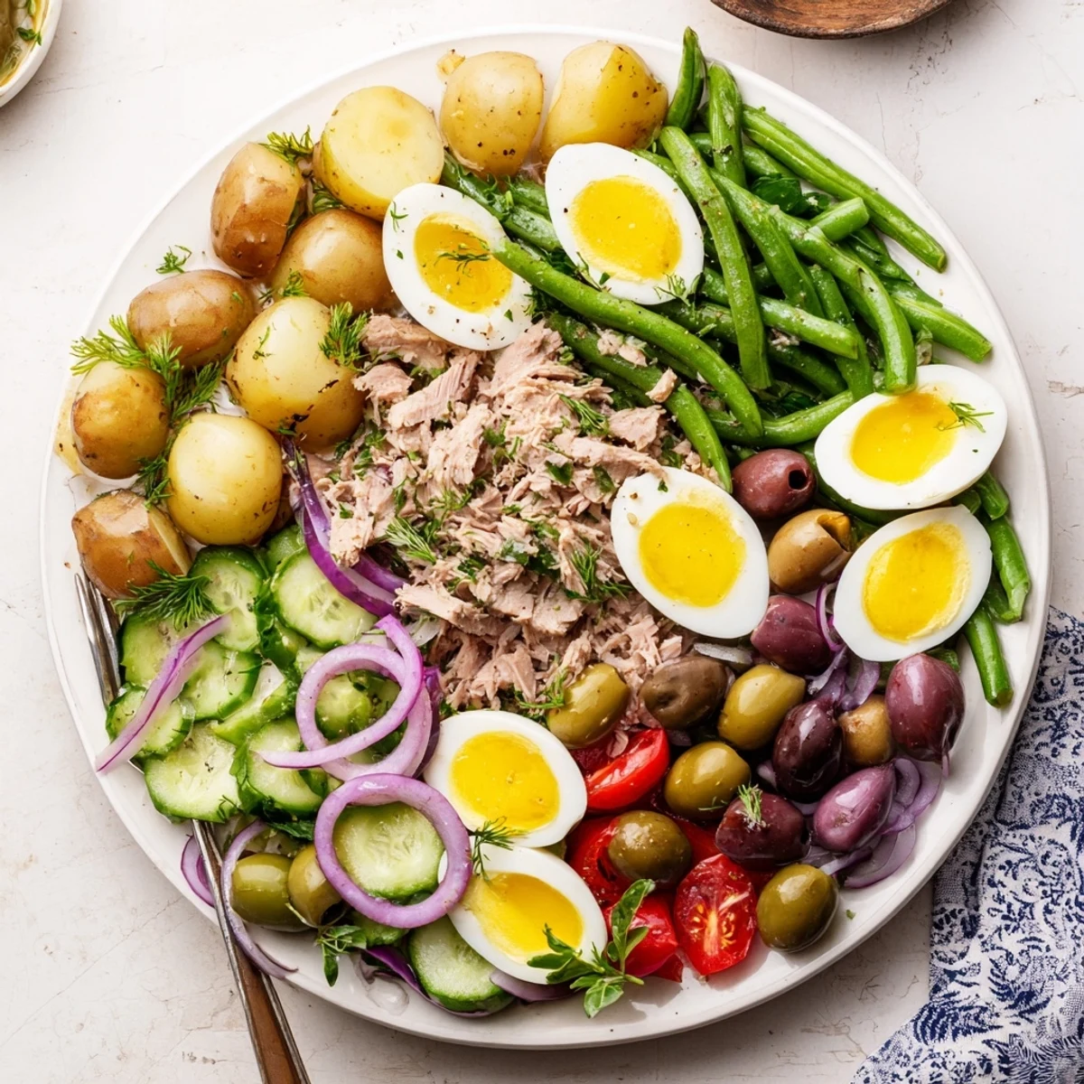 Colorful Niçoise Salad plated with tuna, boiled eggs, olives, crisp vegetables, and tangy vinaigrette dressing