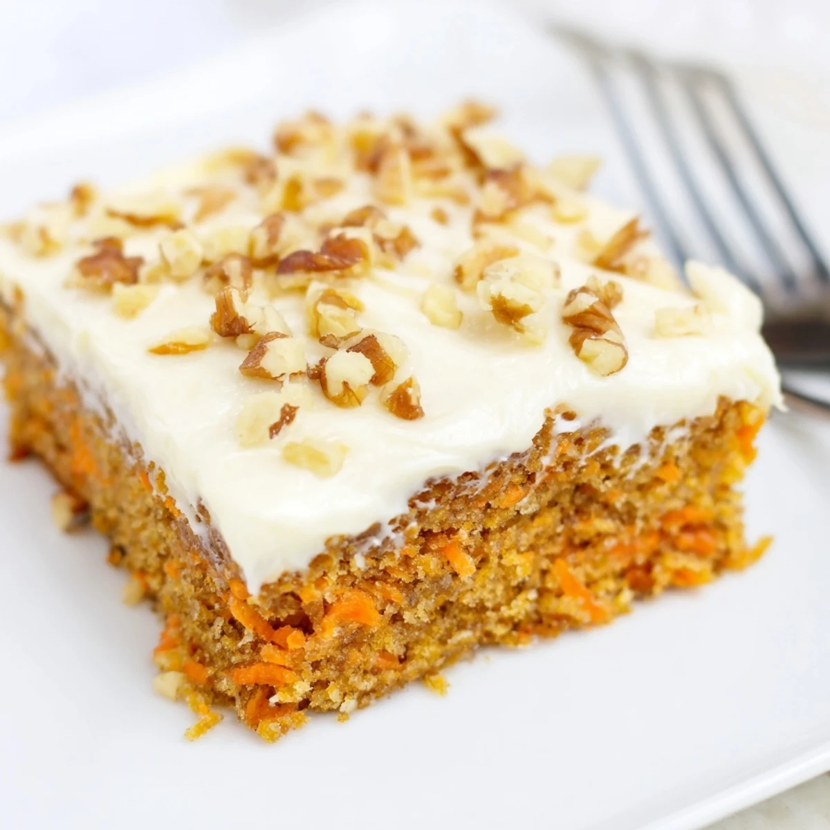 Close-up of rectangular carrot cake bars showing layers of grated carrots and sweet cream cheese topping