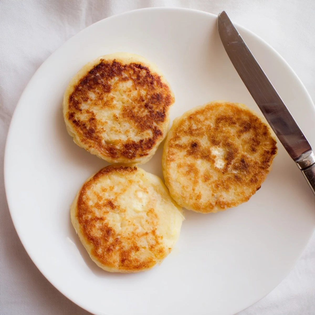 Pan-fried Irish potato cakes displaying fluffY interior and golden crust alongside melted butter