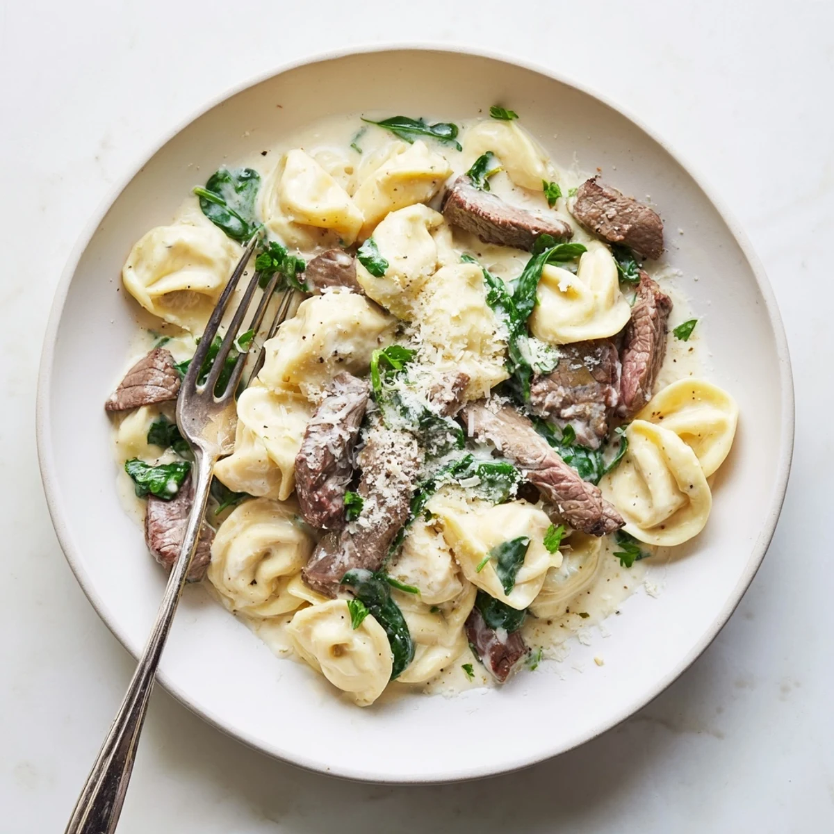 Golden seared steak strips and cheese tortellini coated in rich creamy garlic sauce