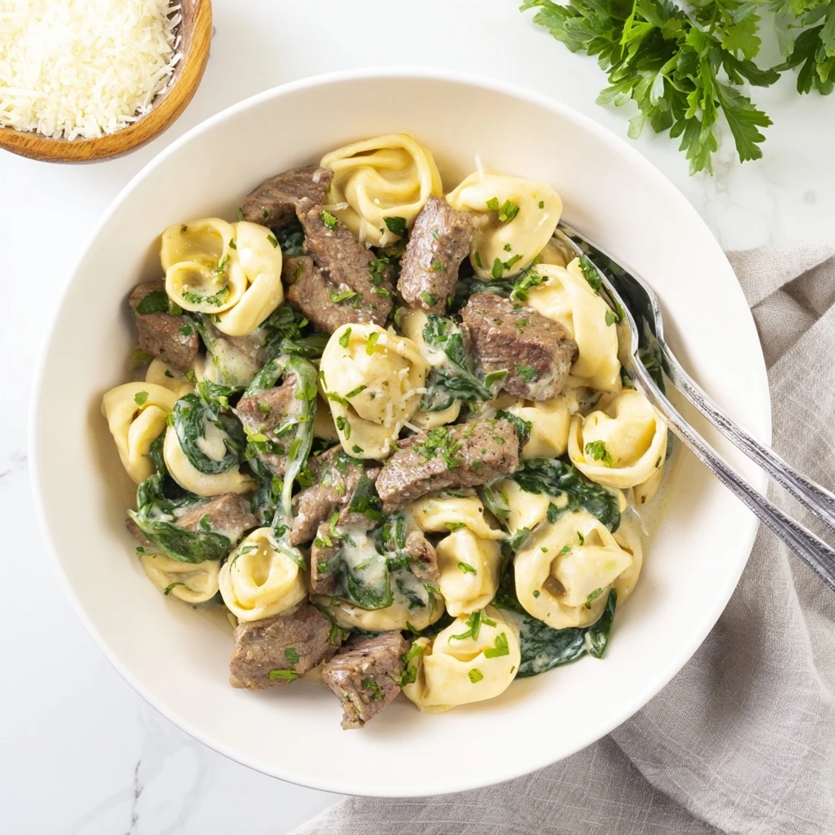Savory garlic steak tortellini tossed with parmesan cream sauce and fresh green spinach