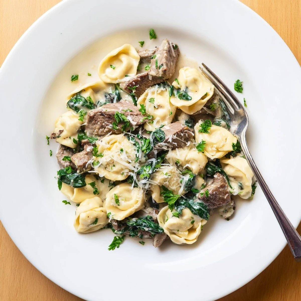 Plated garlic steak tortellini dish featuring tender beef pasta in velvety white cream sauce