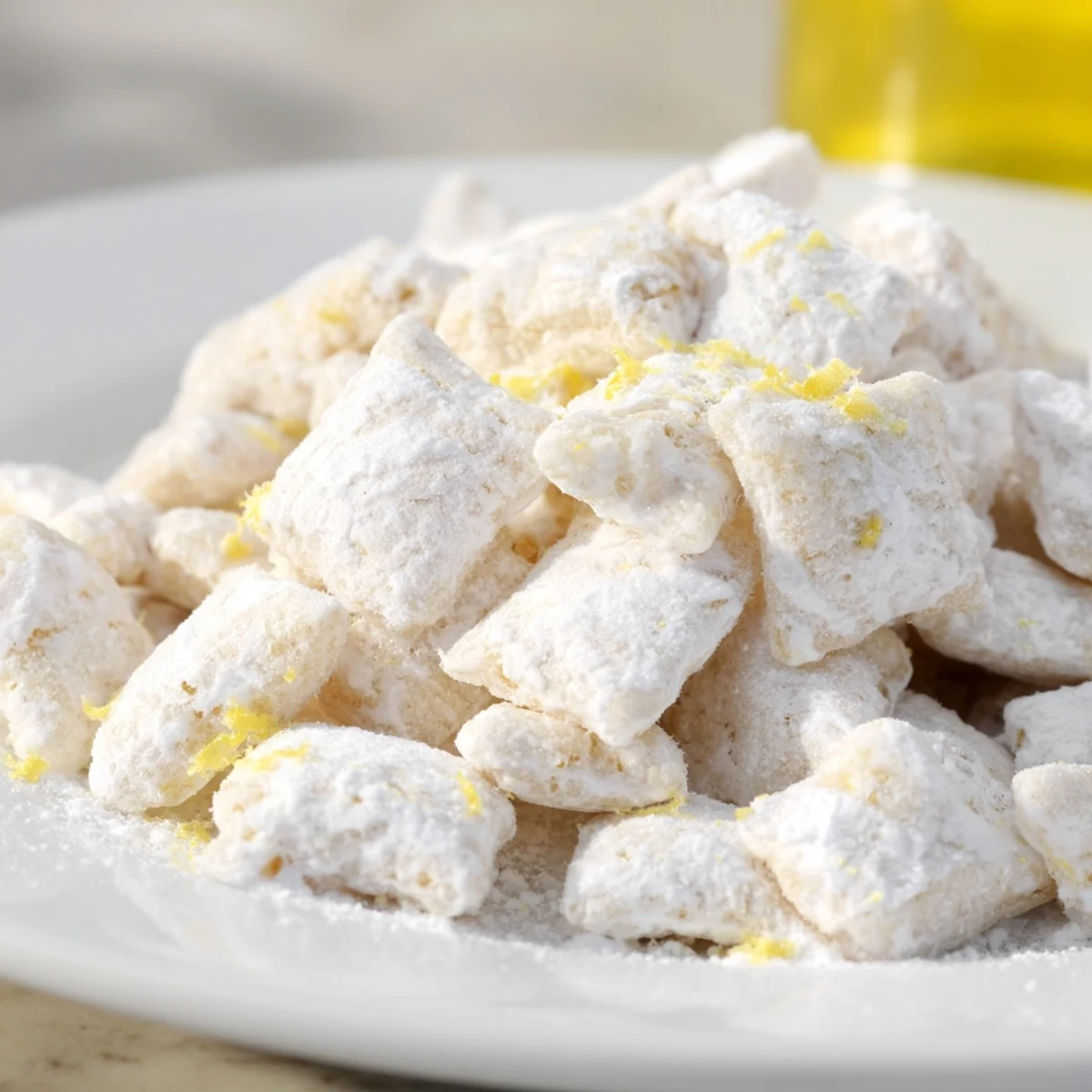 Close up of zesty lemonade puppy chow snack in a glass bowl showing the sugary white coating and yellow lemon garnish