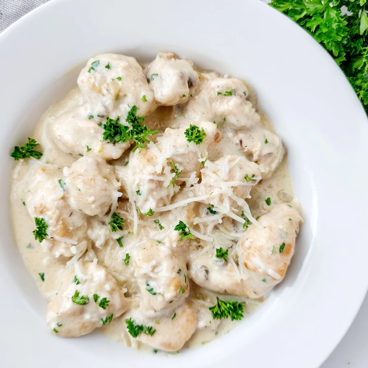 Golden brown chicken breasts swimming in a rich, creamy garlic Parmesan sauce with fresh parsley garnish