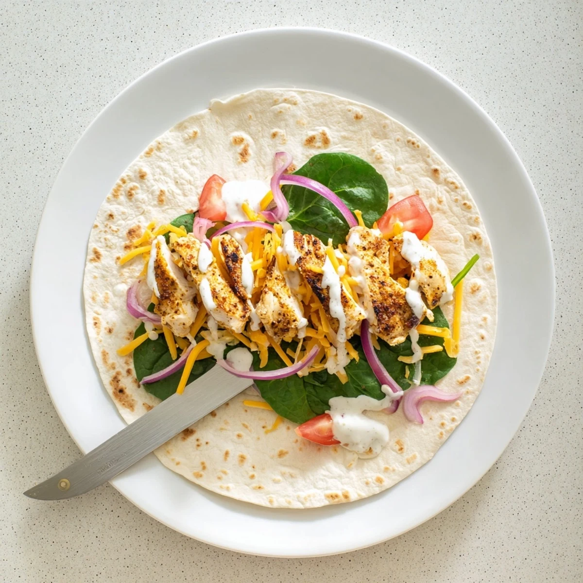 Whole wheat low carb cheesy garlic chicken wraps served on a white plate with tomato garnish