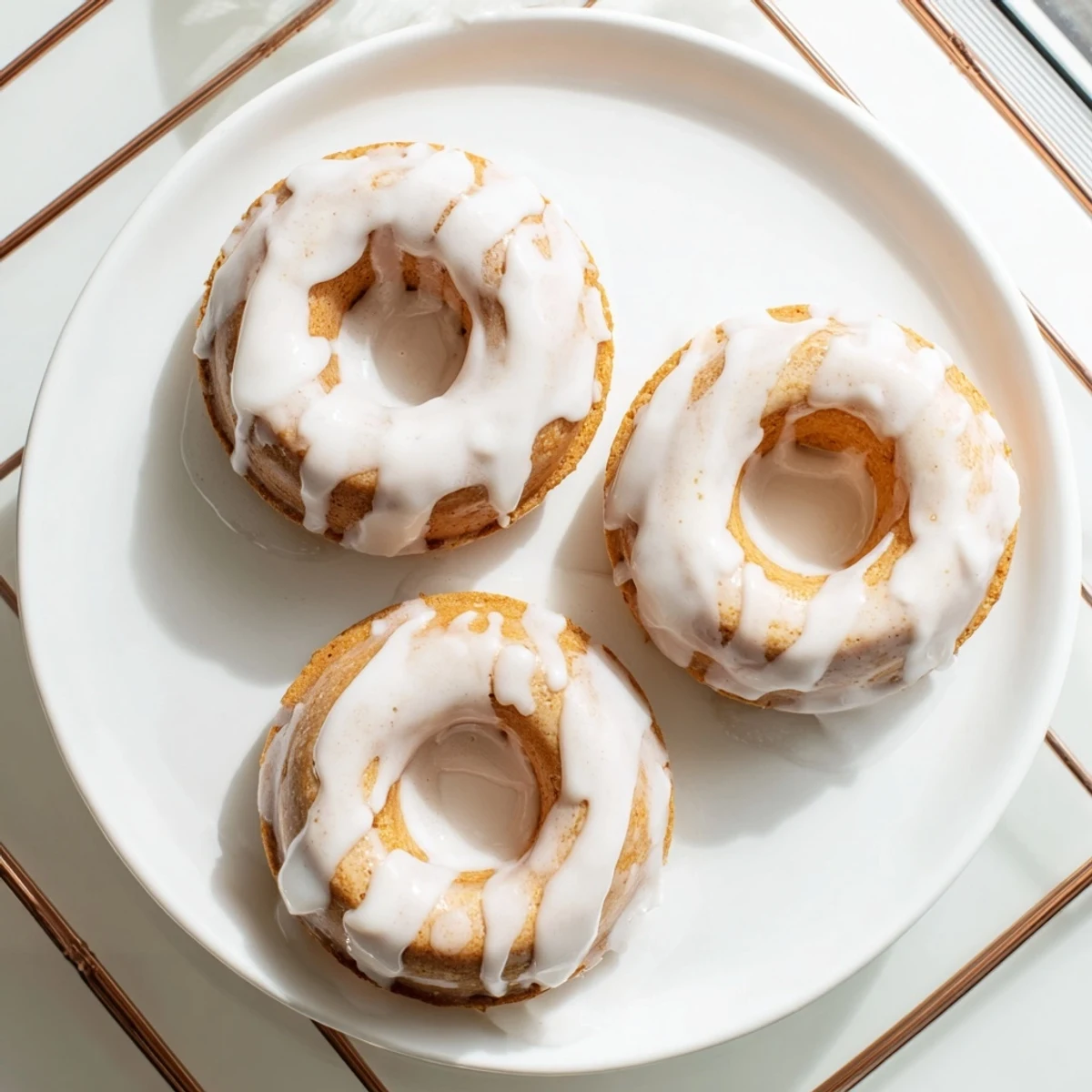 Golden baked Greek yogurt cake donuts topped with sweet vanilla glaze on a wire rack