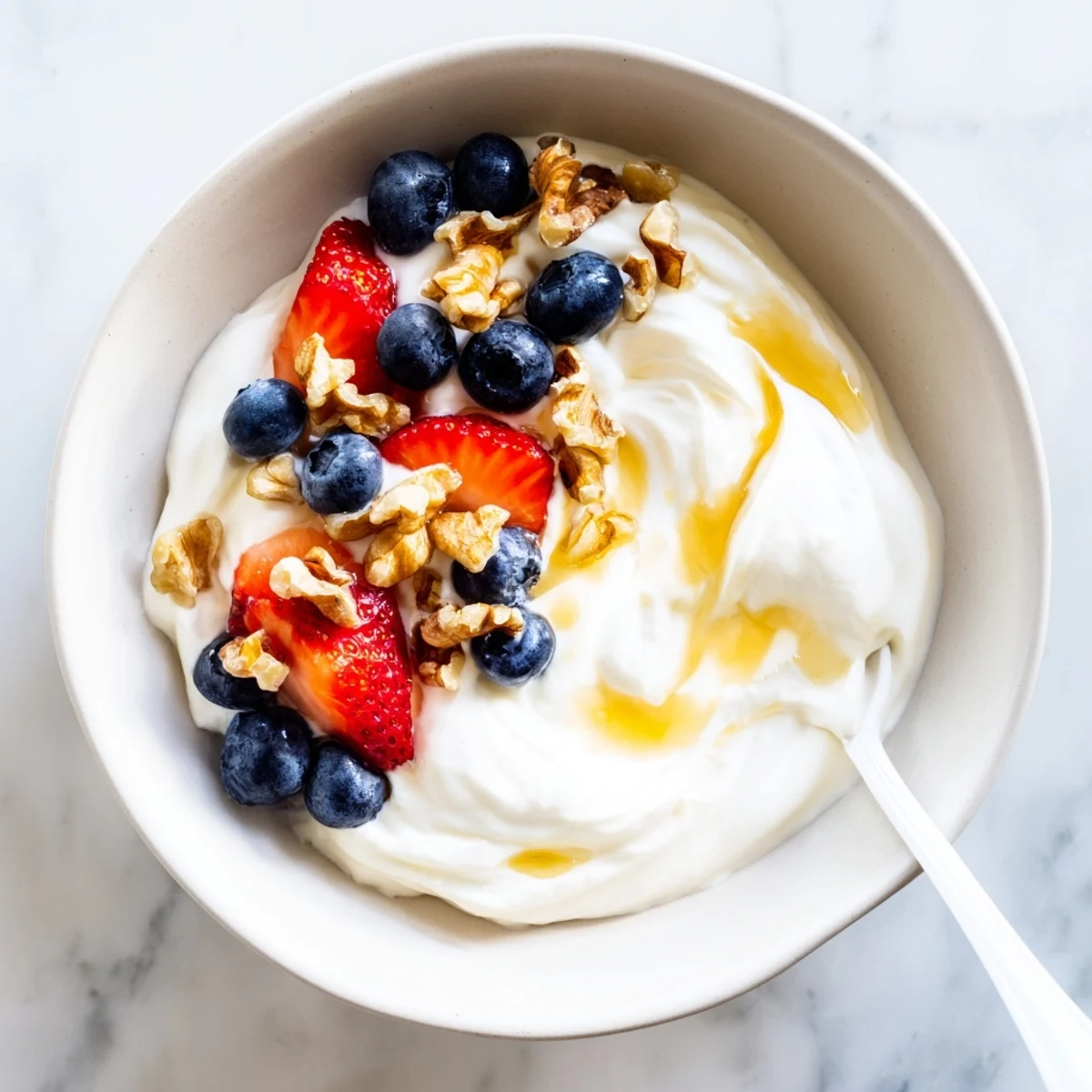 Thick strained Greek yogurt with spoon showing rich texture on wooden kitchen table