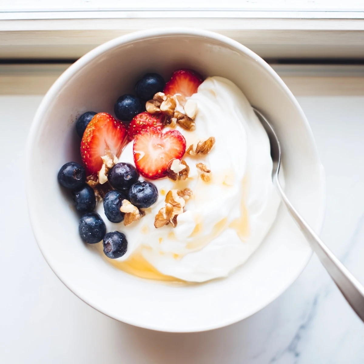 Greek yogurt parfait layered with granola, berries, and honey drizzle in glass jar