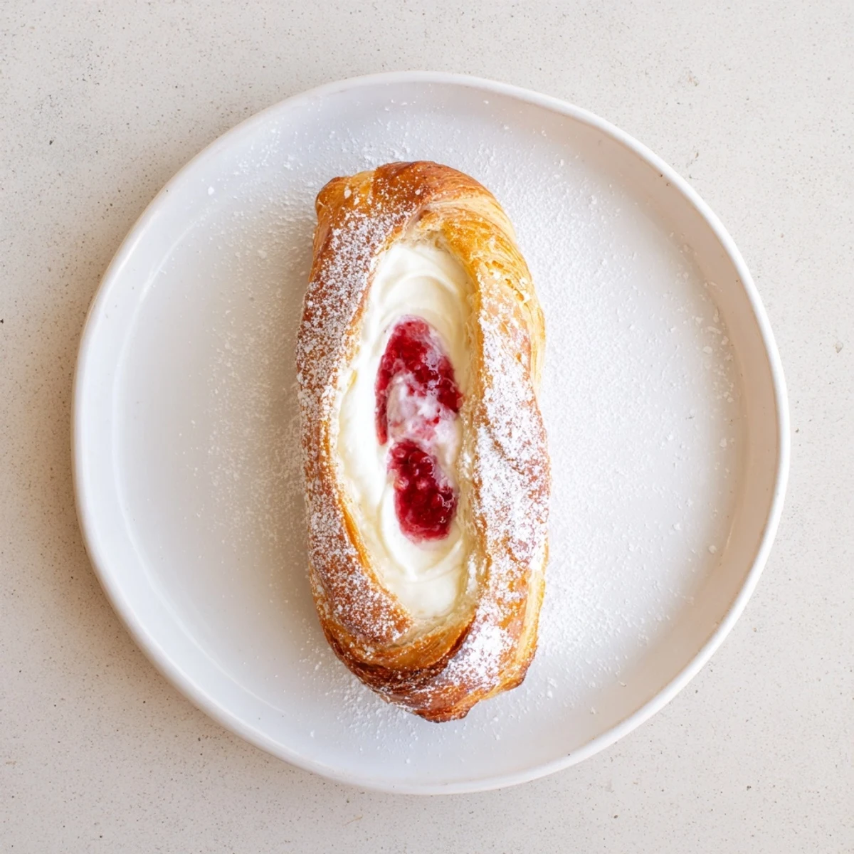 Golden sourdough discard raspberry cream cheese danishes drizzled with sweet vanilla glaze on parchment