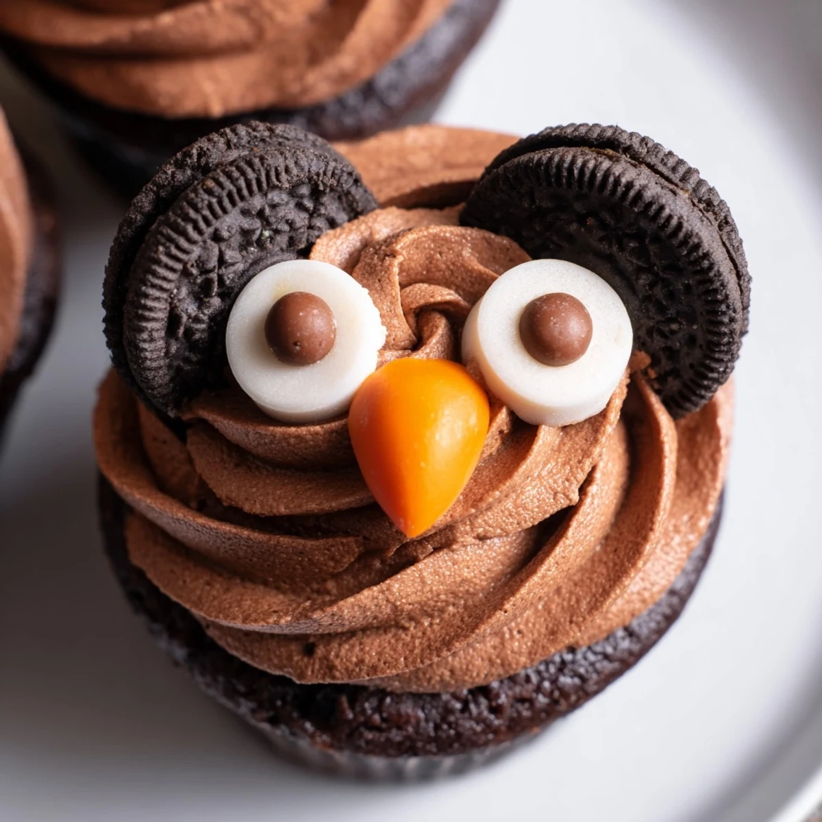 Adorable Oreo Owl Cupcakes displayed on a white platter with rich cocoa frosting and cookie eyes