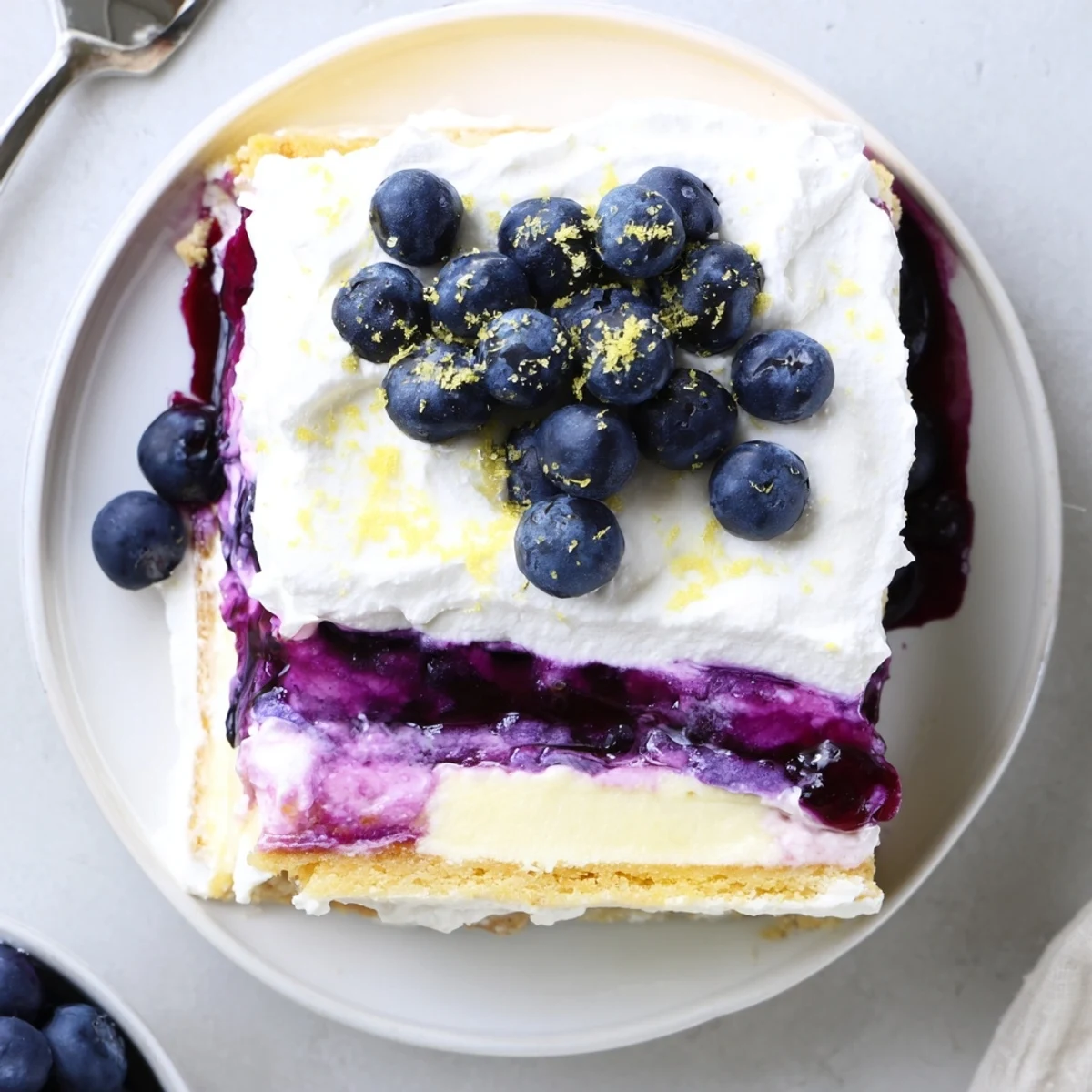 Golden cookie crust beneath vibrant lemon cream and blueberry layers in this refreshing lasagna dessert