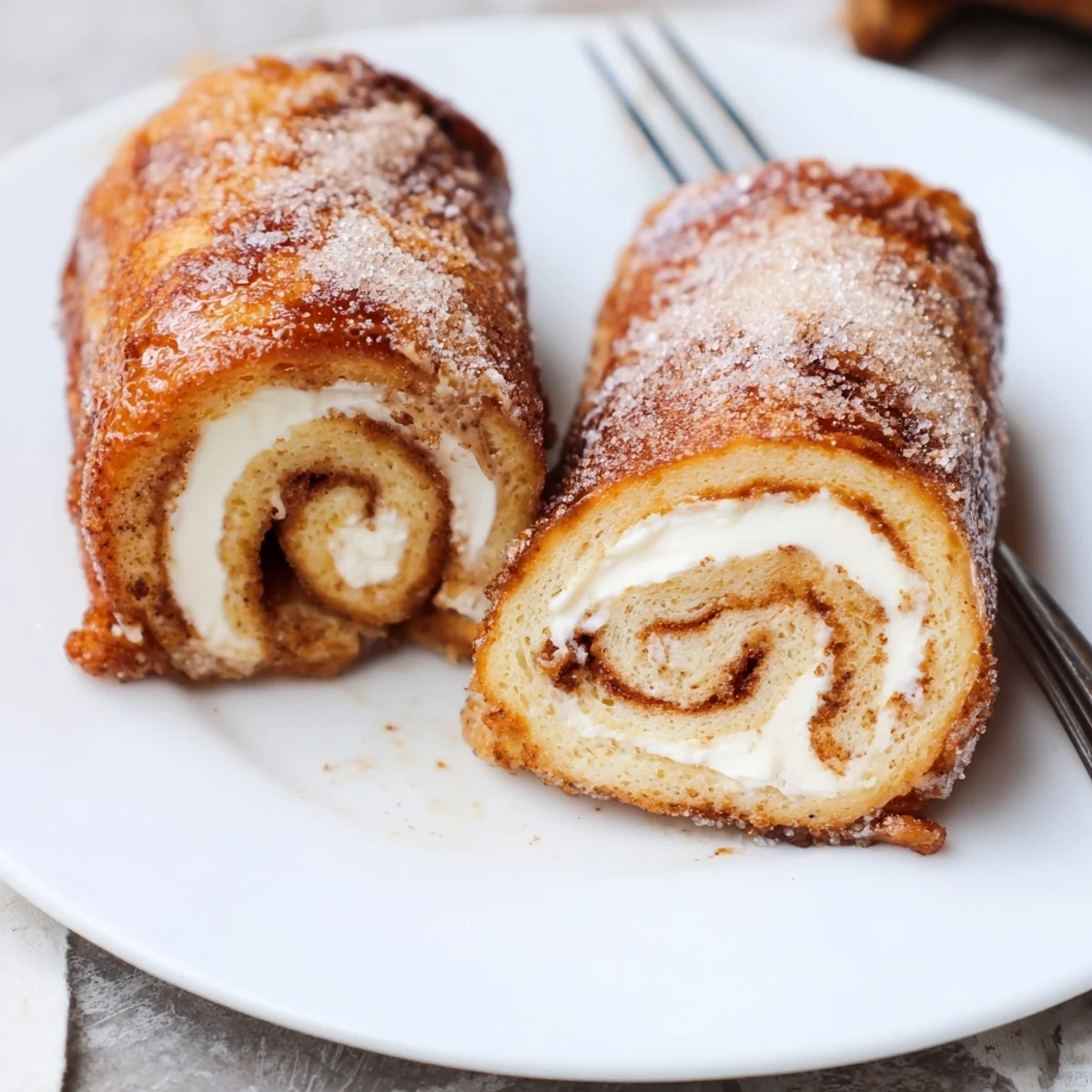 Skillet browned Cinnamon Roll French Toast Roll Ups filled with warm cream cheese