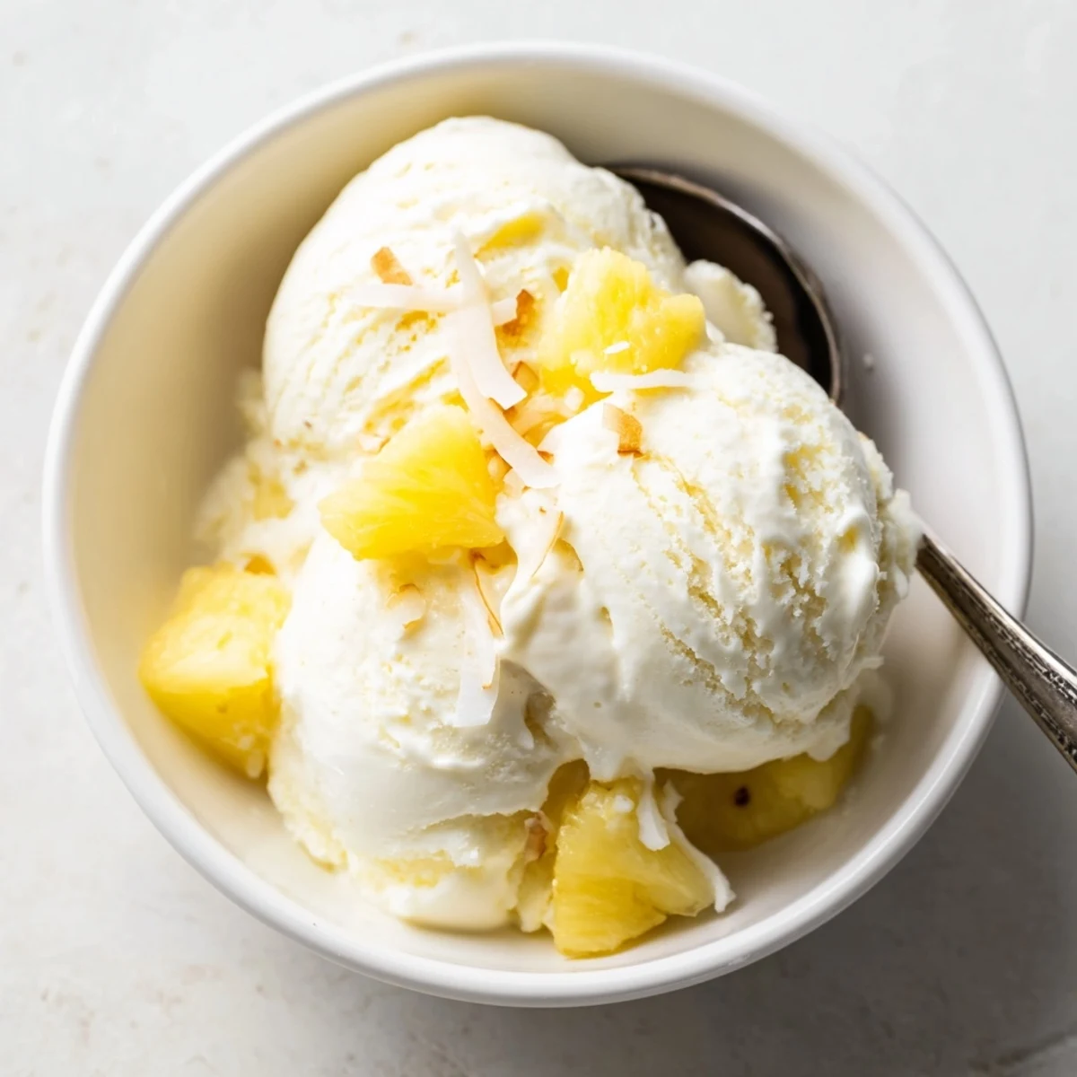 Creamy Pineapple Ice Cream scoops glistening, tropical aroma, served in bowl