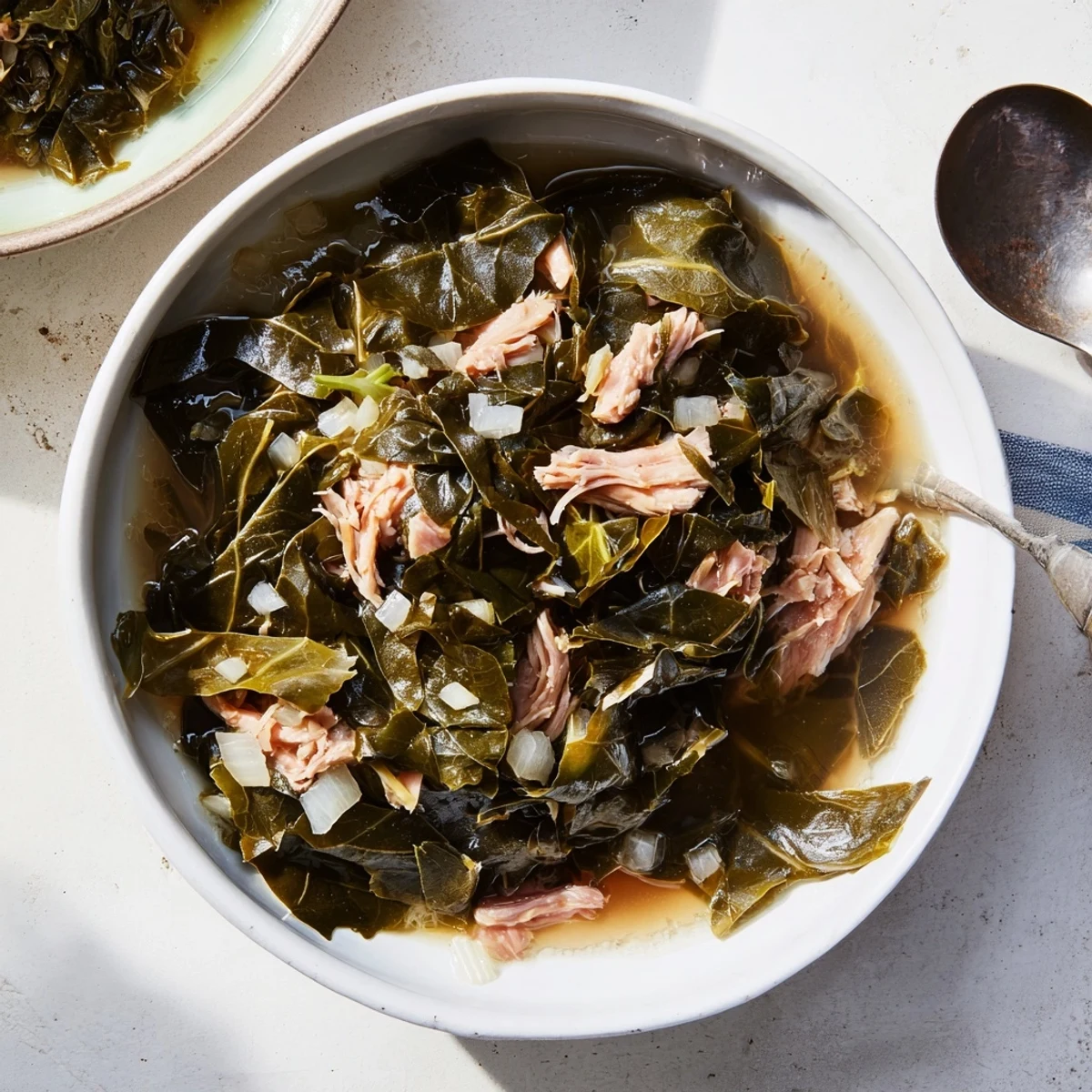 Hearty bowl of slow-cooked Southern collard greens with tender leaves in rich, smoky broth