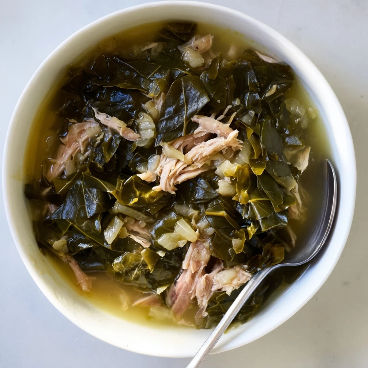 Traditional Southern collard greens dish featuring wilted leaves in a flavorful dark cooking liquid