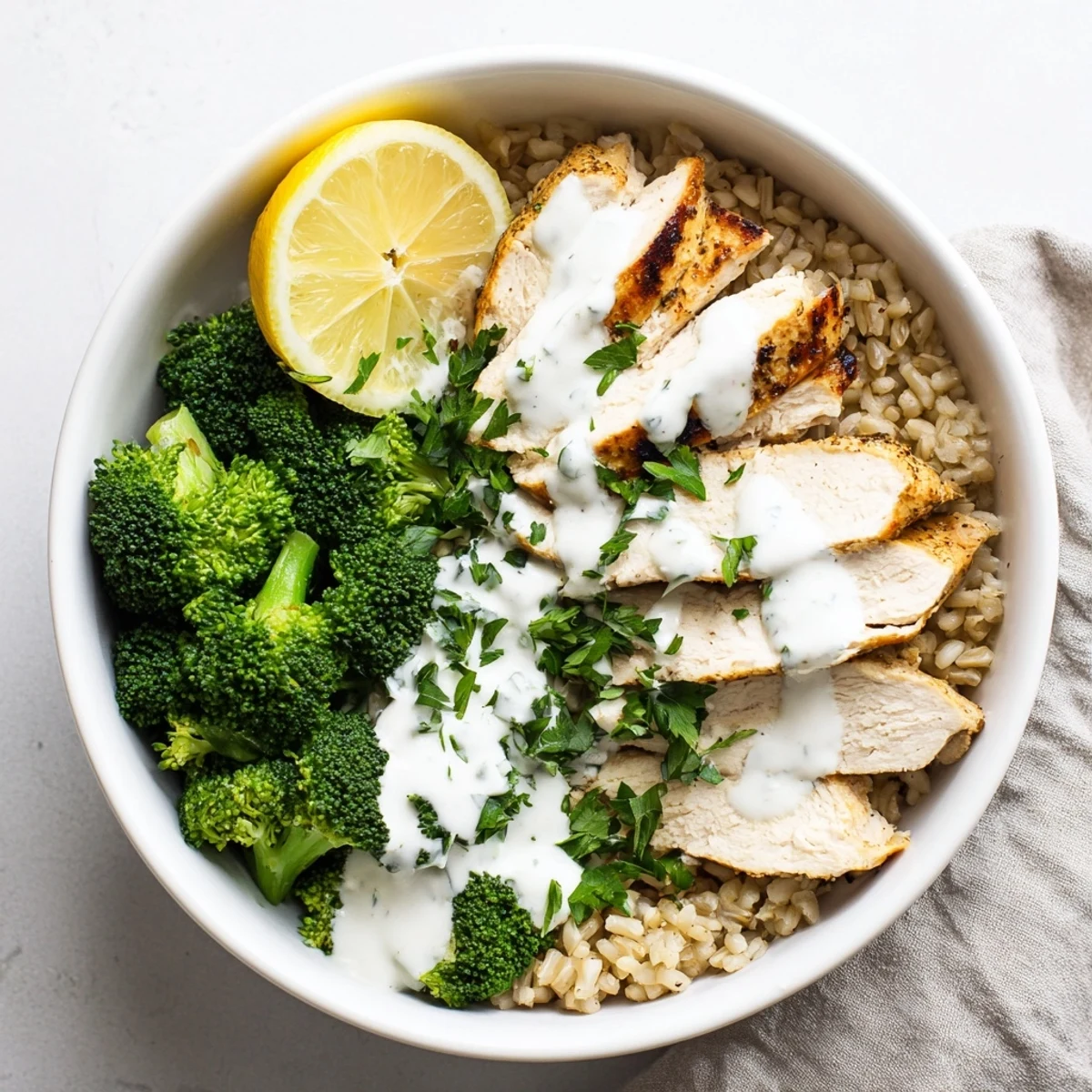 Flavorful healthy grilled chicken broccoli bowls with tender protein and creamy garlic drizzle on top.