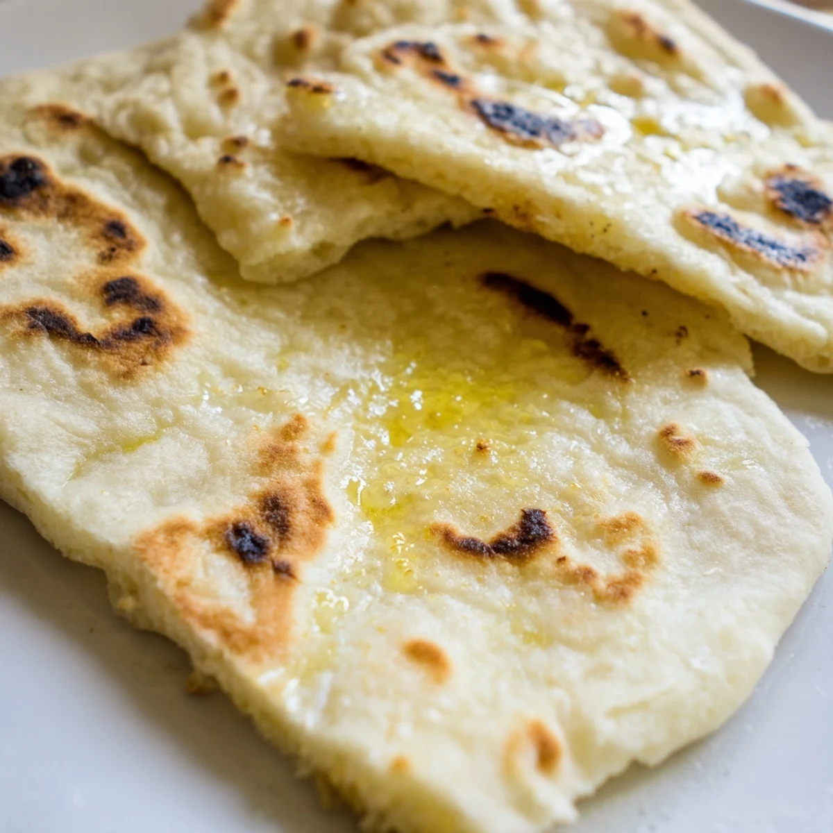 Golden Turkish Bazlama flatbread with pillowy soft interior and lightly charred surface, perfect for dipping in warm spreads