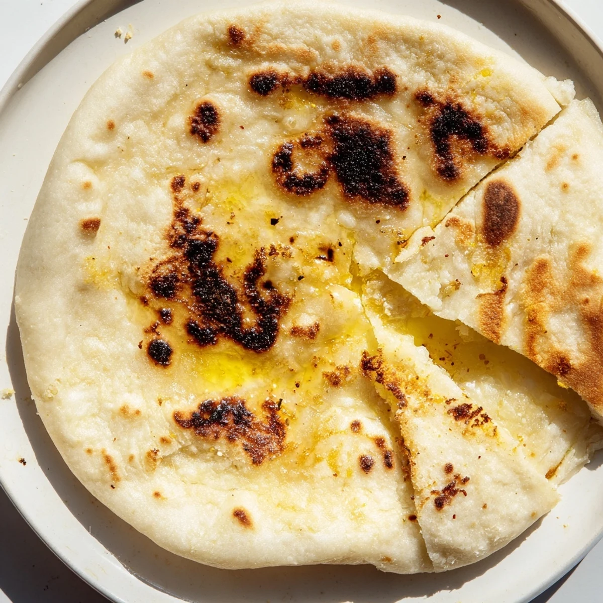 Handmade Turkish Bazlama flatbread stacked high on a wooden board, featuring signature air pockets and golden-brown grilled exterior