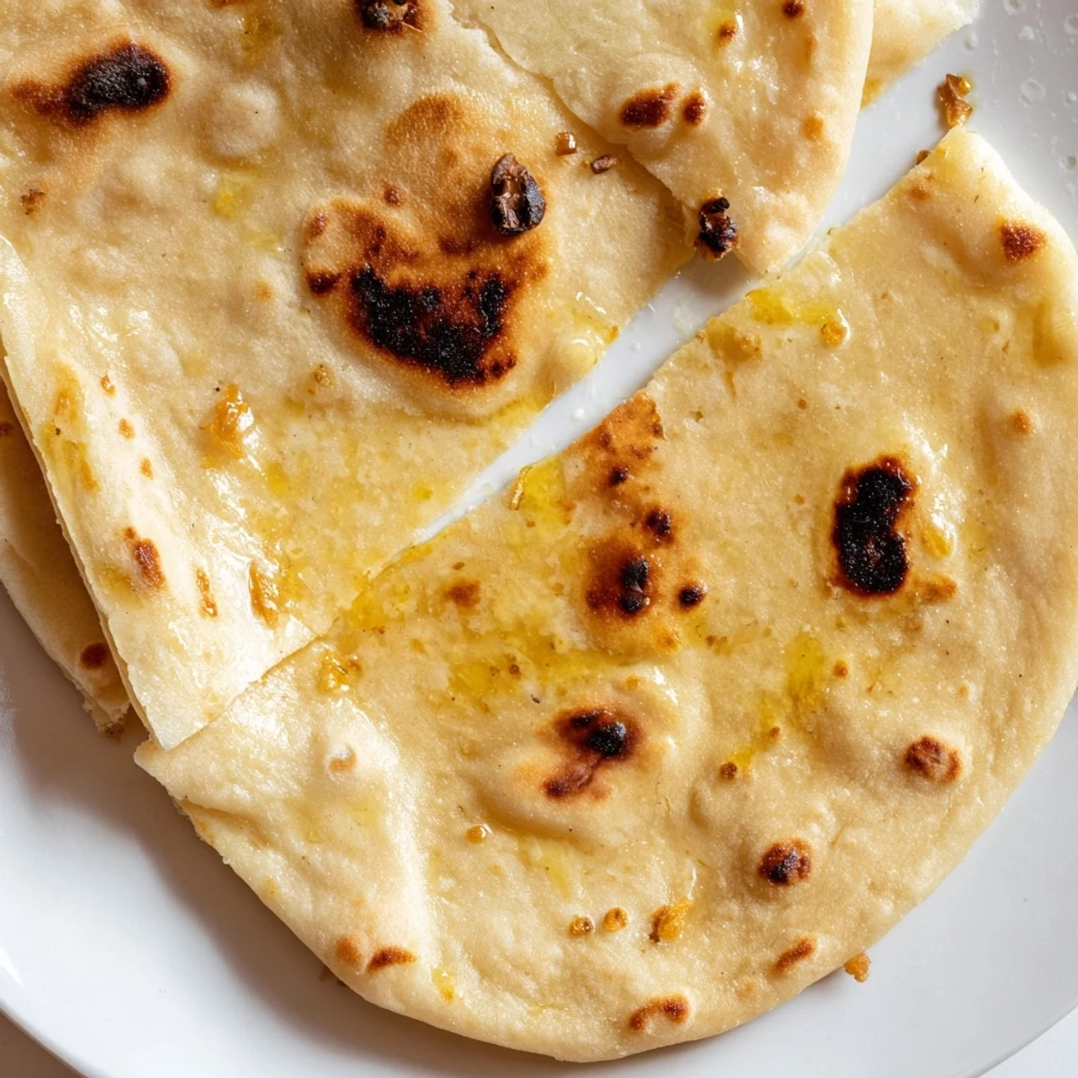 Freshly cooked Turkish Bazlama bread brushed with olive oil, showcasing its soft chewy texture ideal for wraps or scooping dips