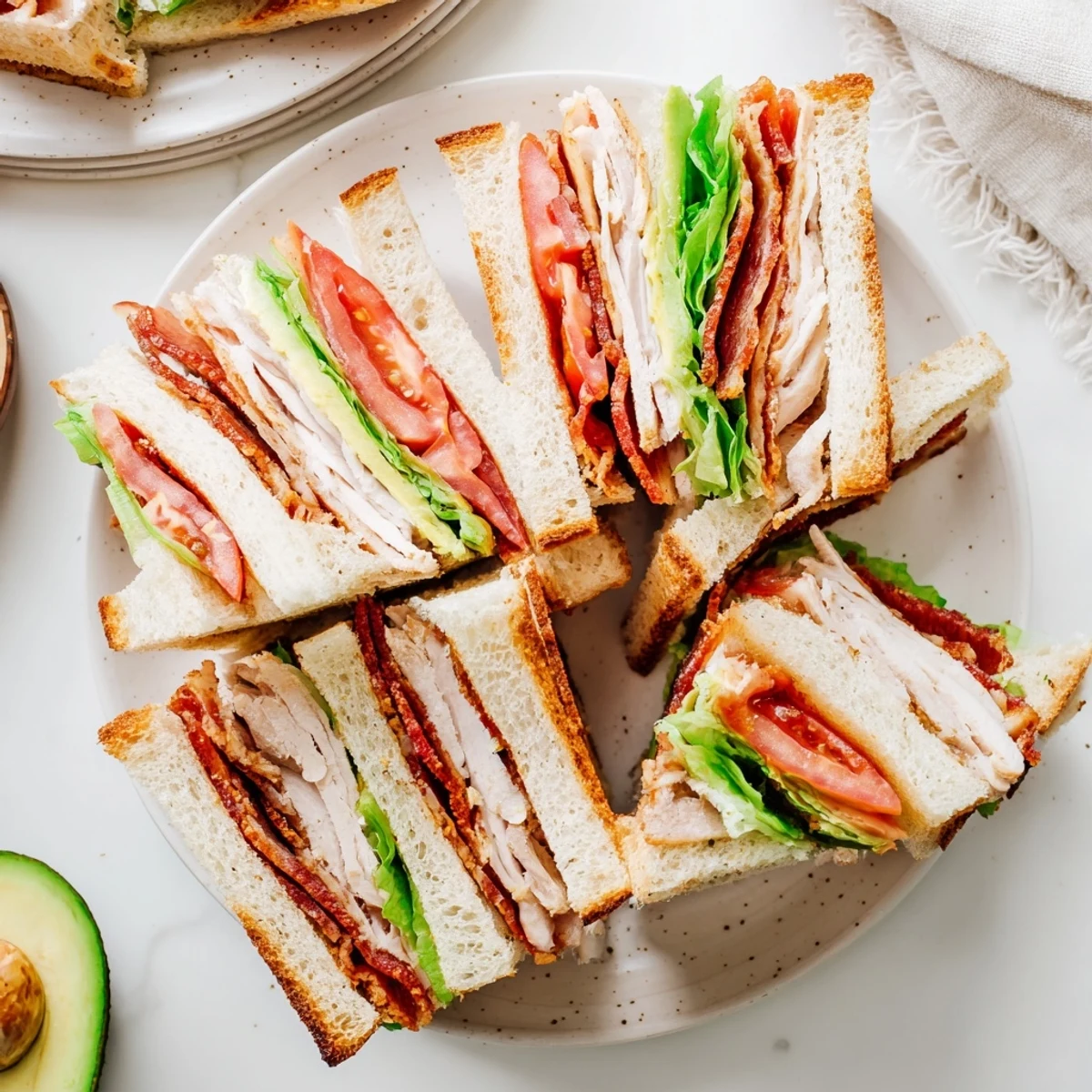 Triple-decker California Club Sandwich stacked with roasted turkey, crispy bacon, avocado, and fresh tomato on toasted bread